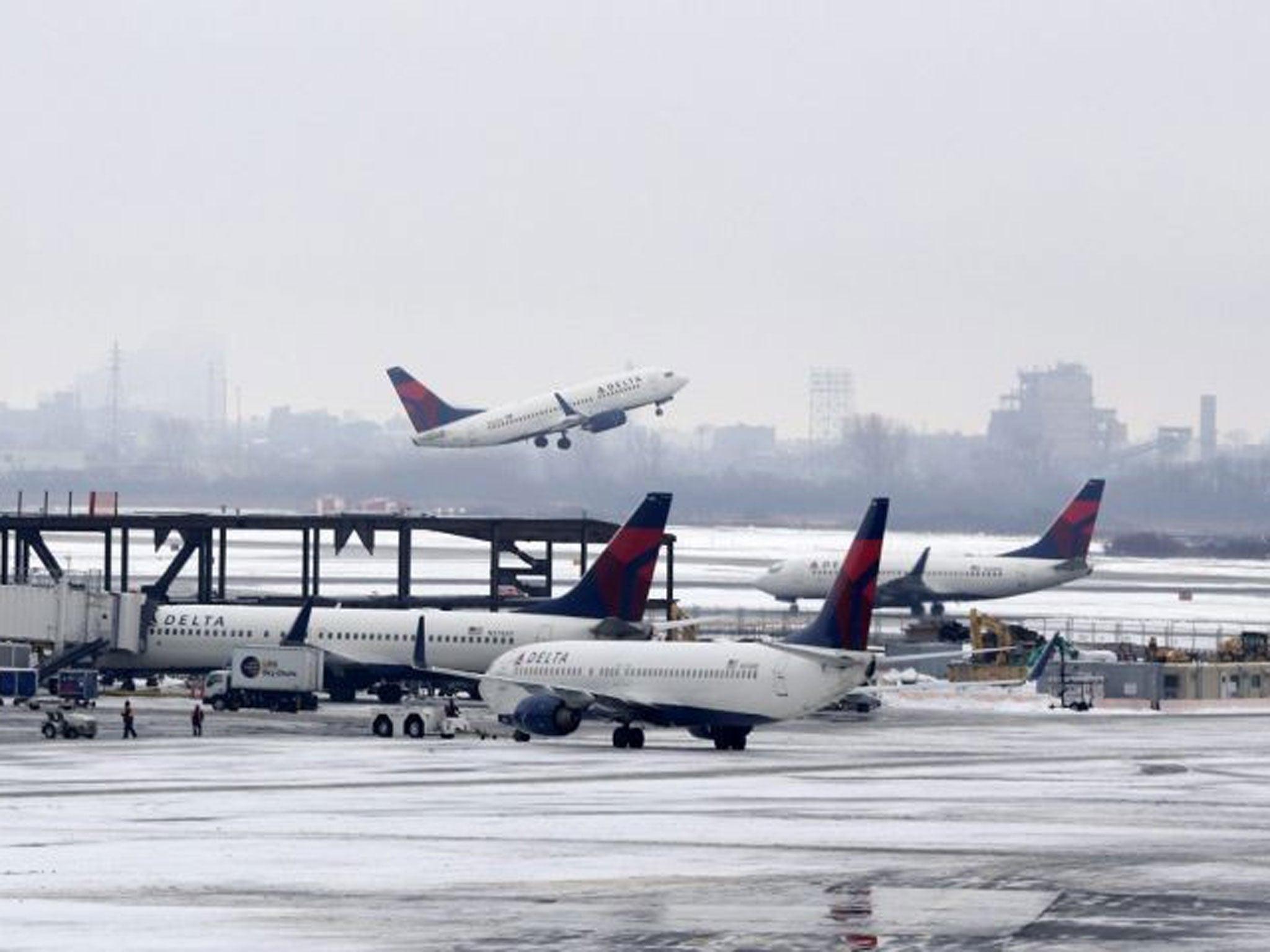 A Delta airlines plane is seen taking off while the fleets other planes sit on the tarmac at JFK Airport, New York