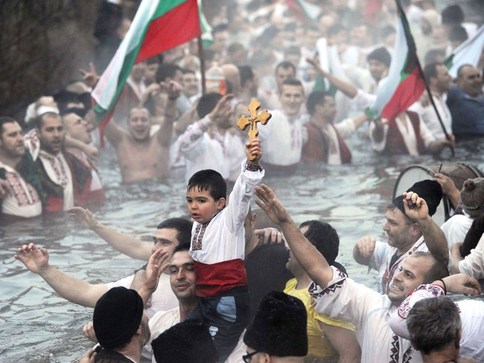 A Bulgarian boy holds a wooden cross during the traditional dance in the icy winter waters of the Tundzha river in the town of Kalofer, as part of the Epiphany Day celebrations