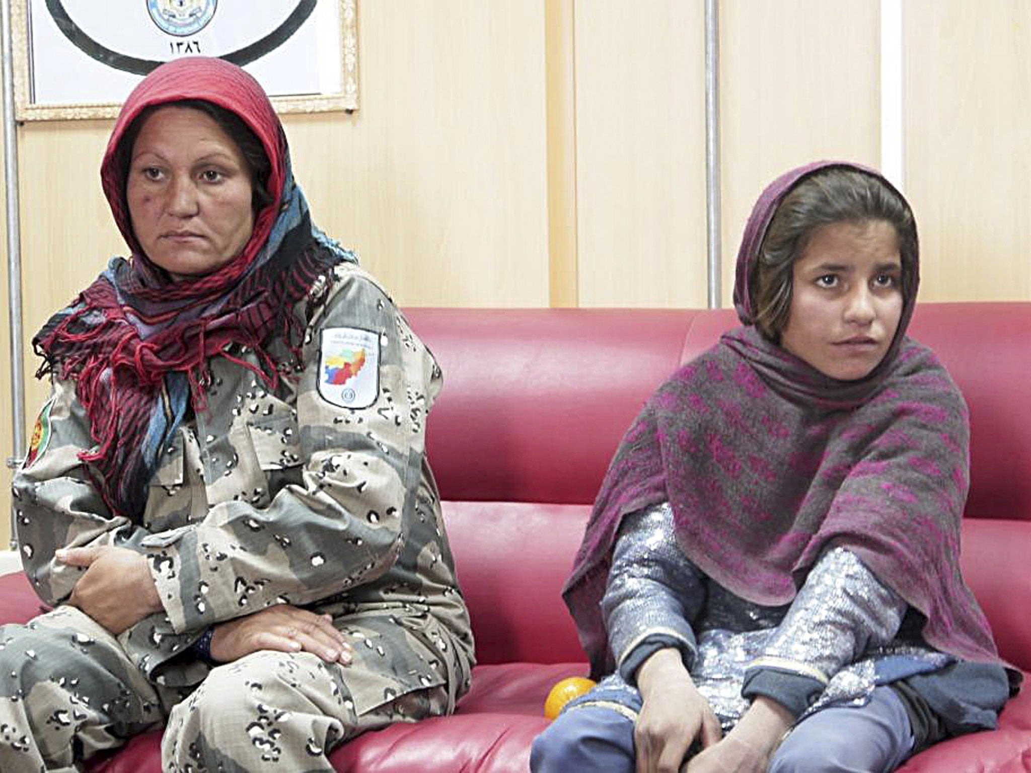 Sphozmay, 10, who was about to be used by the Taliban as a suicide bomber, sits next to a police officer at a police office in Helmand province