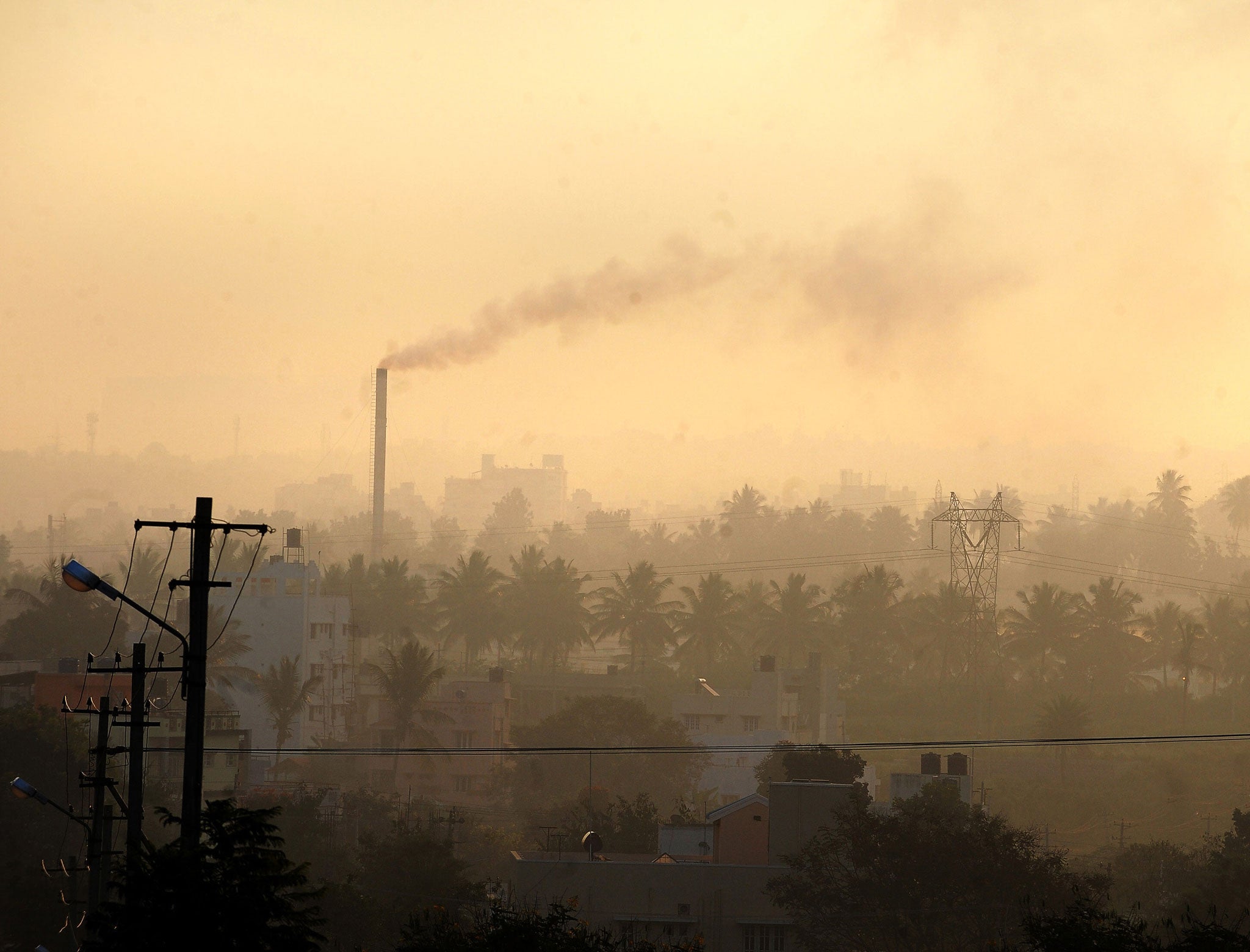 A factory chimney in a residential area emits smoke as haze casts a blanket over Bangalore