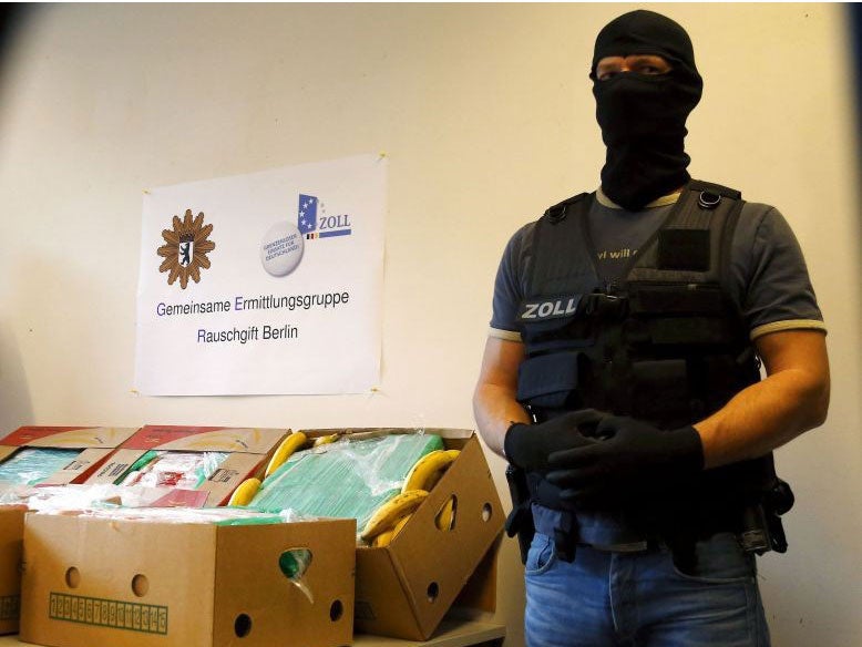 A German police officer poses next to a table laden with the confiscated cocaine