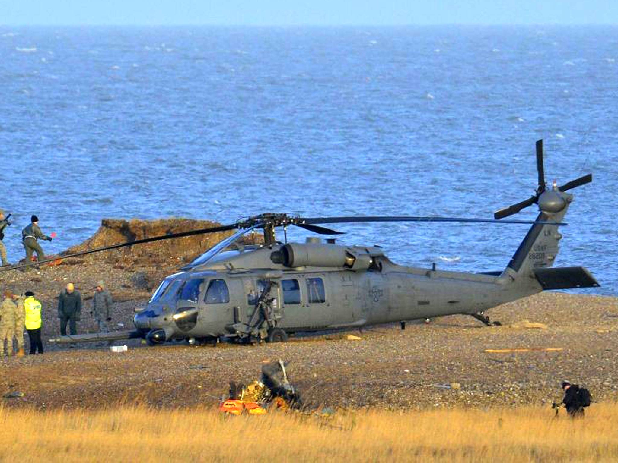 A Pave Hawk helicopter, military personnel and emergency services attend the scene of the crash on the coast near Cley