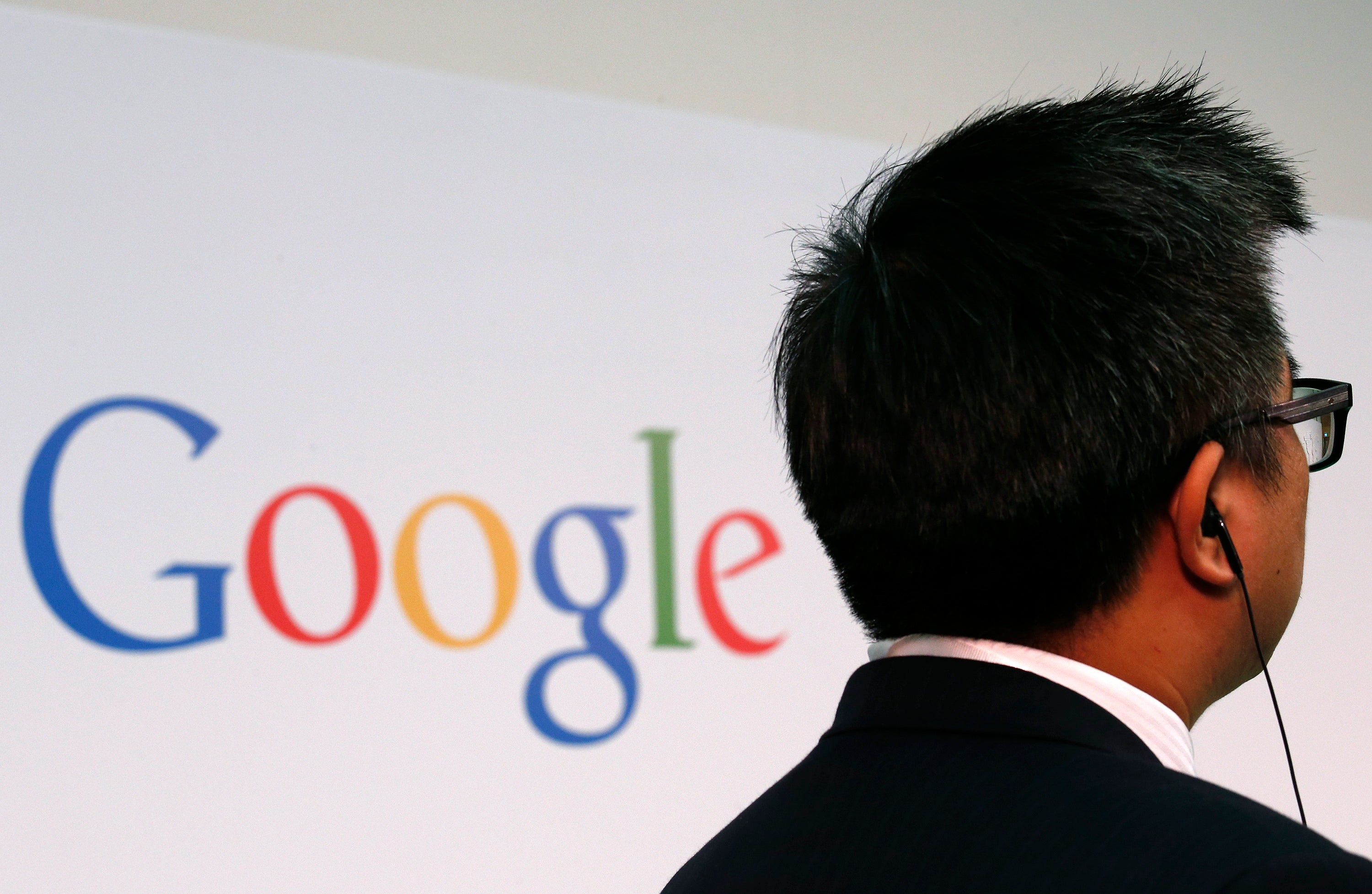 A man stands in front of a Google logo.