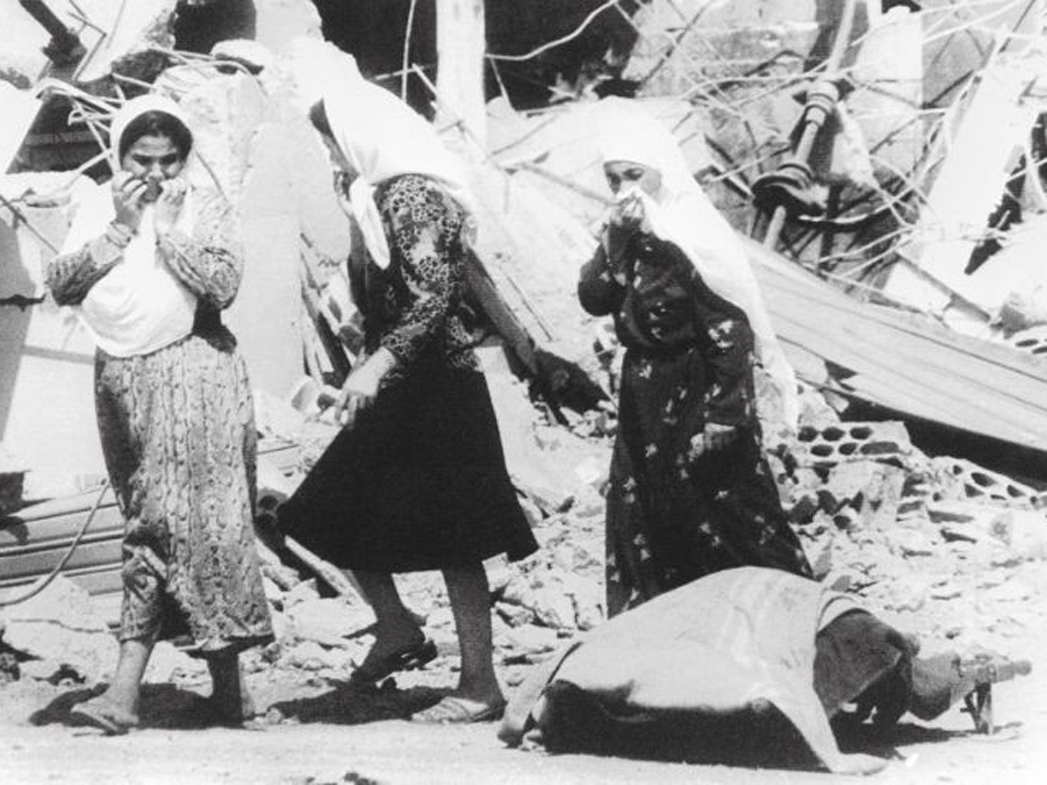 Palestinian women pass the body of one of the victims of the massacres in the Palestinian refugee camp of Sabra