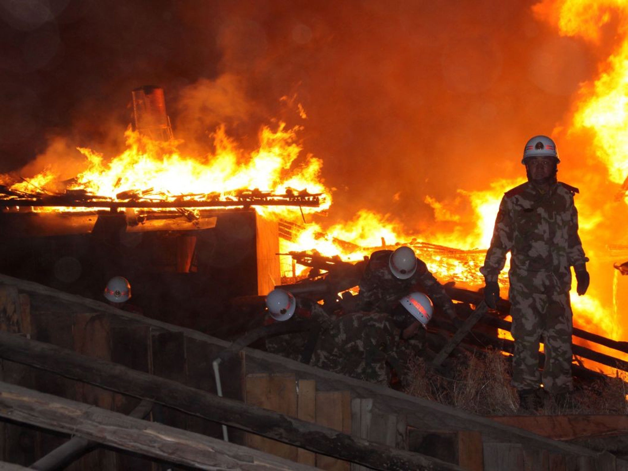 Chinese firefighters work to put out a fire in the ancient Tibetan village of Dukezong