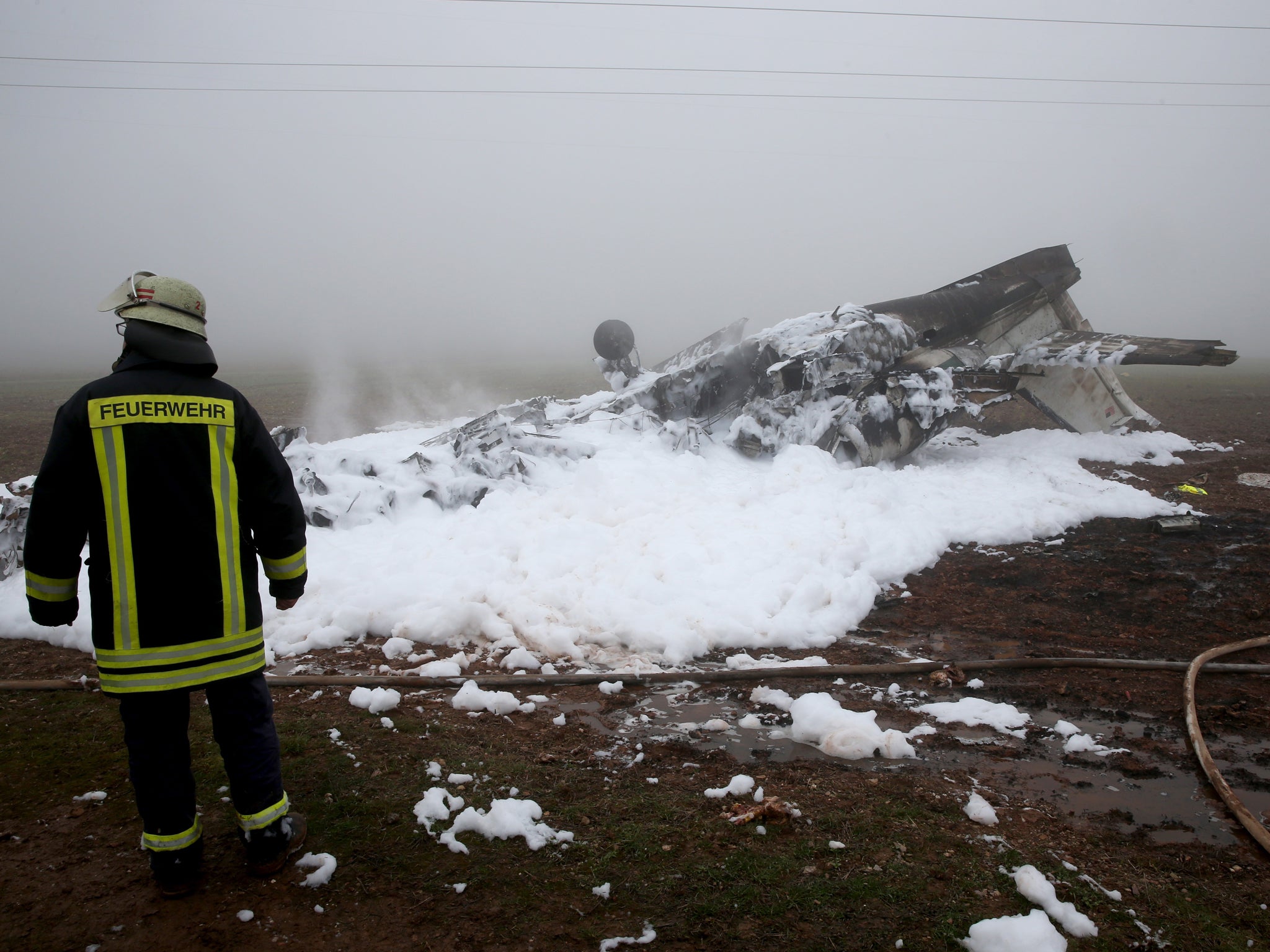 Firefighters inspect the burnt-out wreckage of the twin-engine business jet on the premises of a landfill site in western Germany