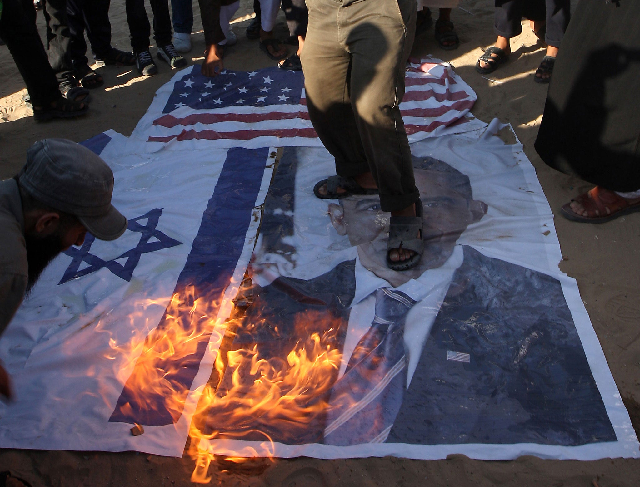 Palestinian Salafists walk on top of a picture of US President Barack Obama while burning Israeli and US flags during a protest against an amateur film mocking Islam in Rafah in the southern Gaza Strip on September 14, 2012