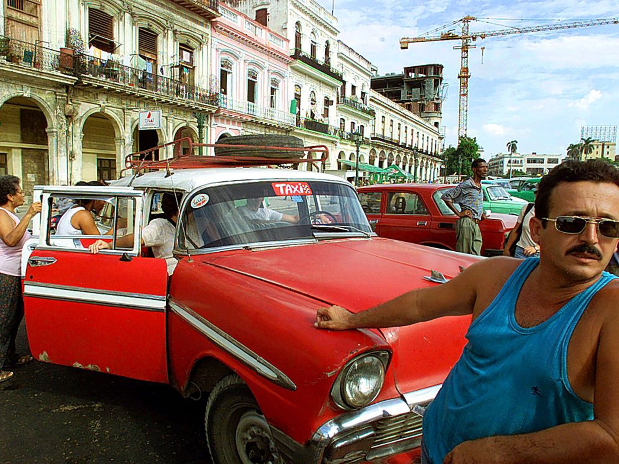 Cuban wheels: a taxi driver waits by his classic car