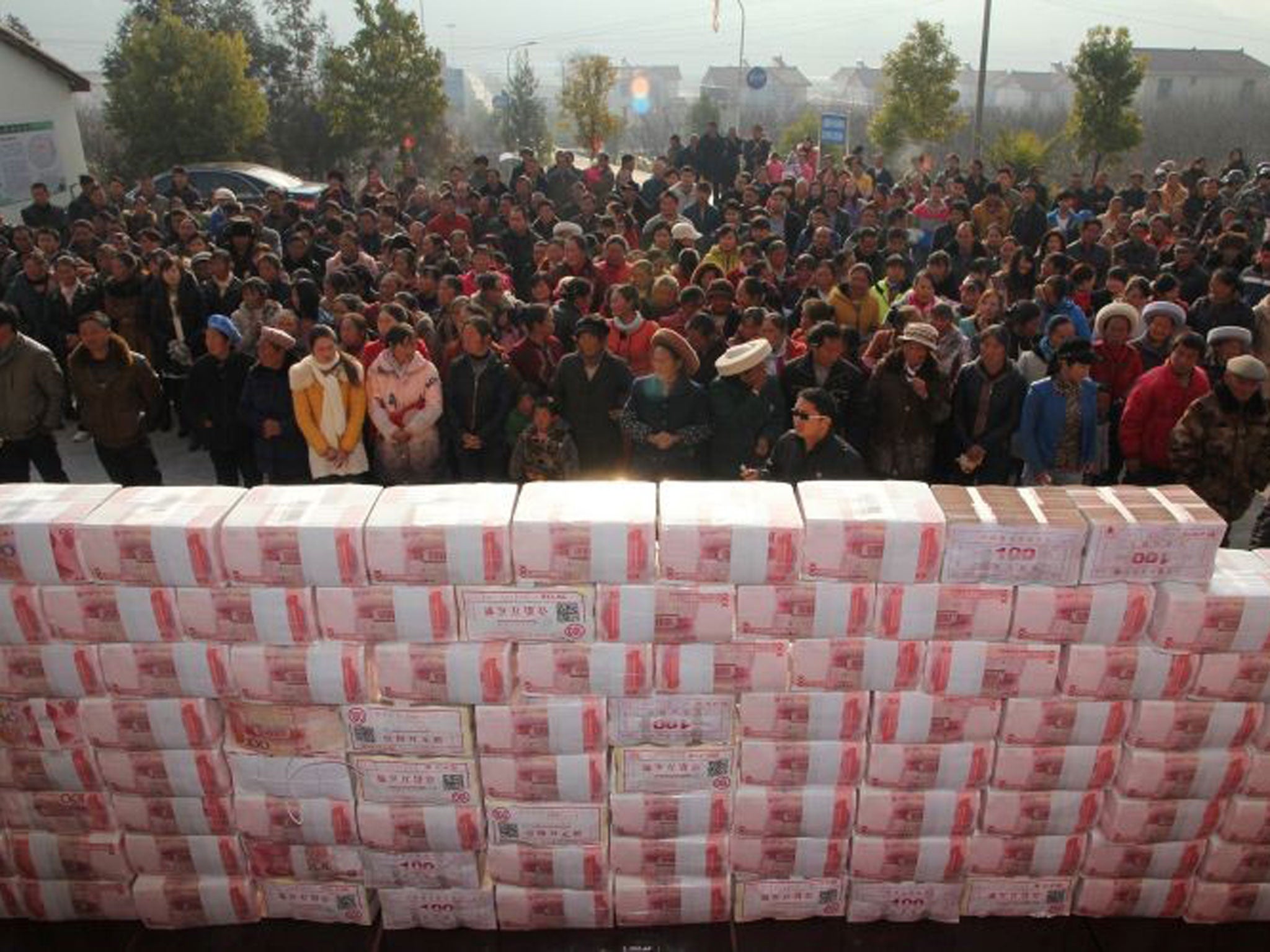 This picture taken on 14 January, 2014 shows villagers waiting before a two-metre-long "money wall" built with cash for their year-end bonus at Jianshe village of Lianshan municipality, southwest China's Sichuan province