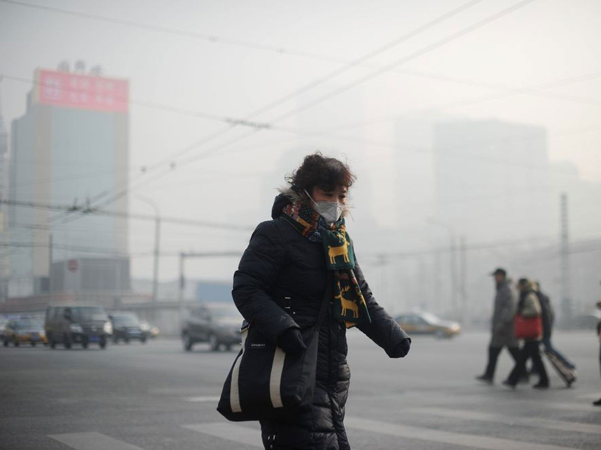 A woman wearing a face mask makes her way along a street in Beijing on Thursday, 16 January