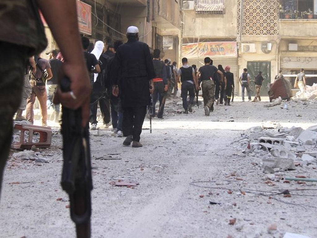 Free Syrian Army fighters carry their weapons as they walk towards the frontline in the refugee camp of Yarmouk, near Damascus