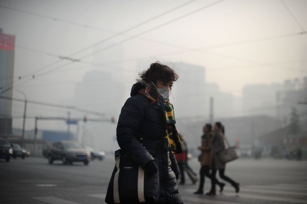 A woman wearing a face mask makes her way along a street in Beijing