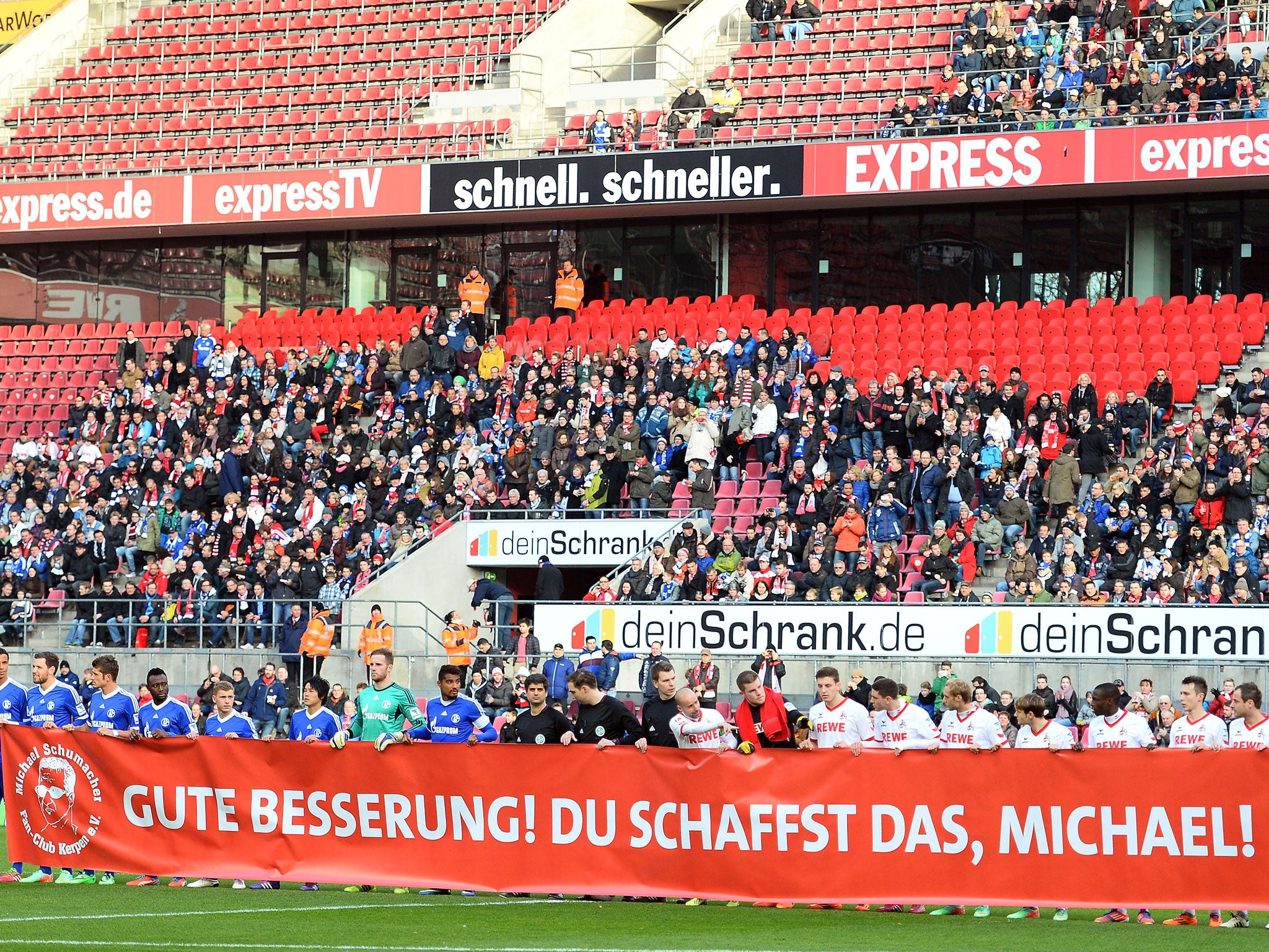 Players from Cologne (R) and Schalke (L) hold up a banner in tribute to Michael Schumacher