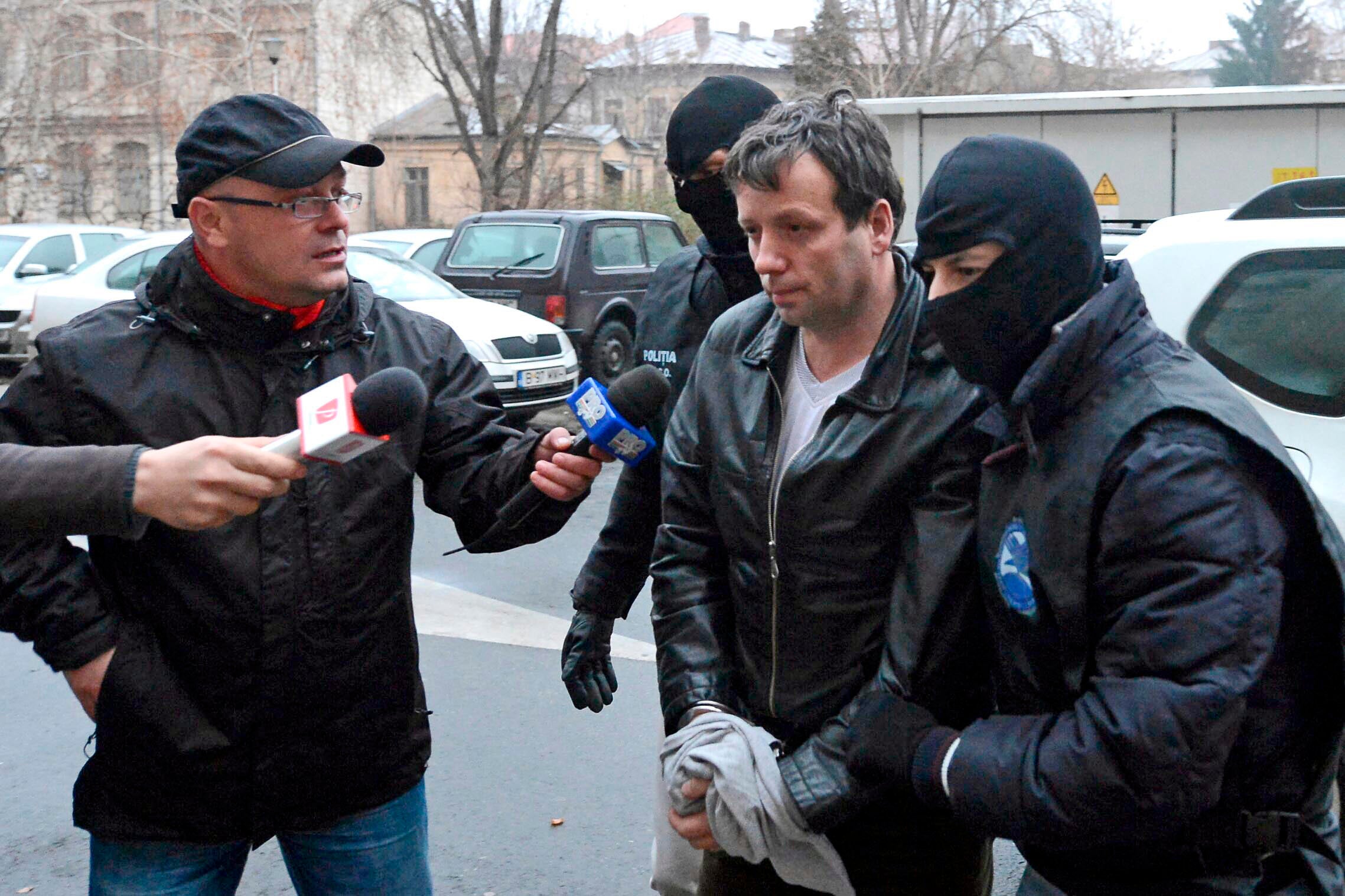 Marcel Lazar Lehel is escorted by masked policemen in Bucharest, after being arrested in Arad, west of Bucharest, on January 22, 2014