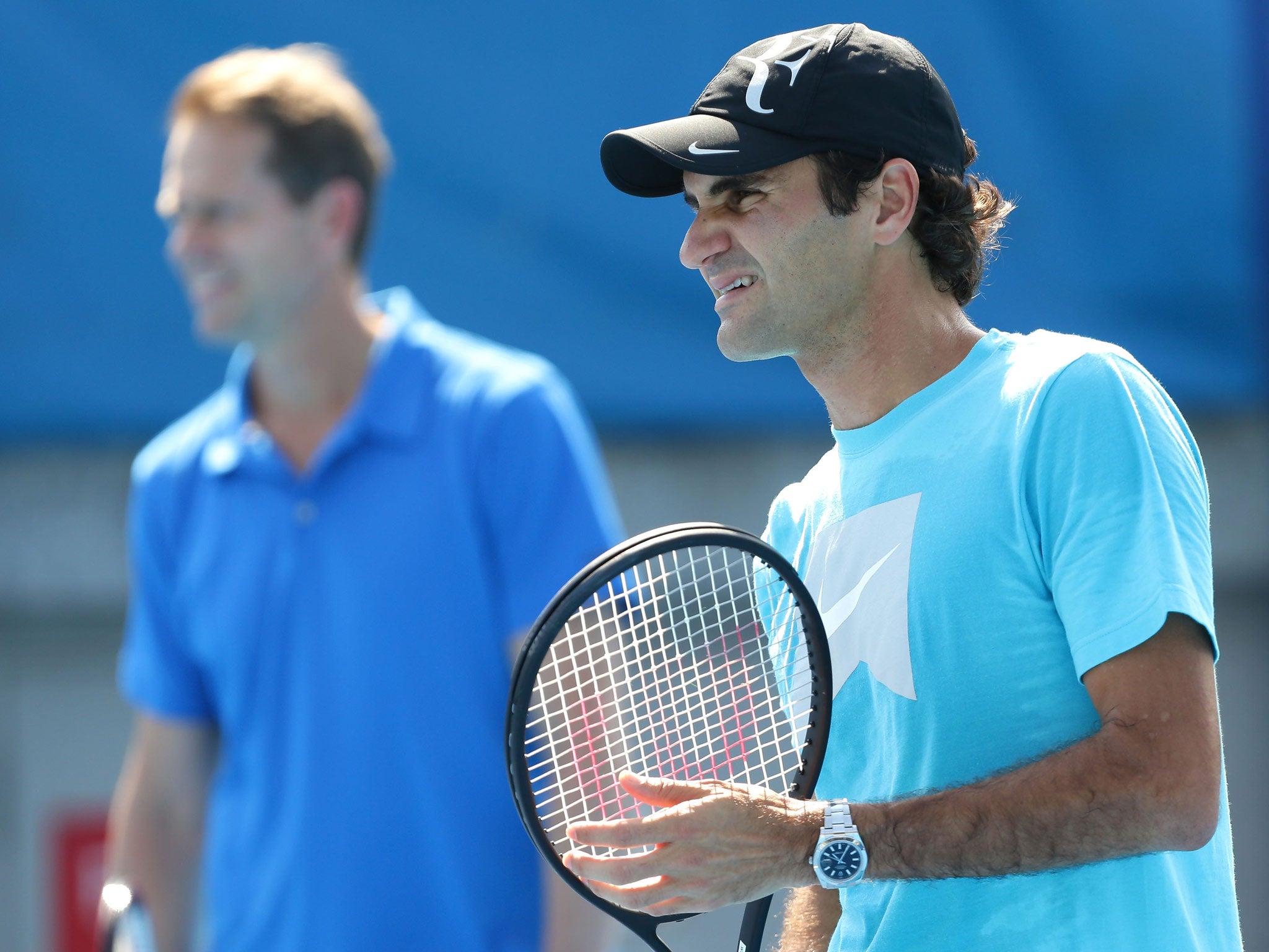 Roger Federer of Switzerland trains in a practice session as his coach, Stefan Edberg watches