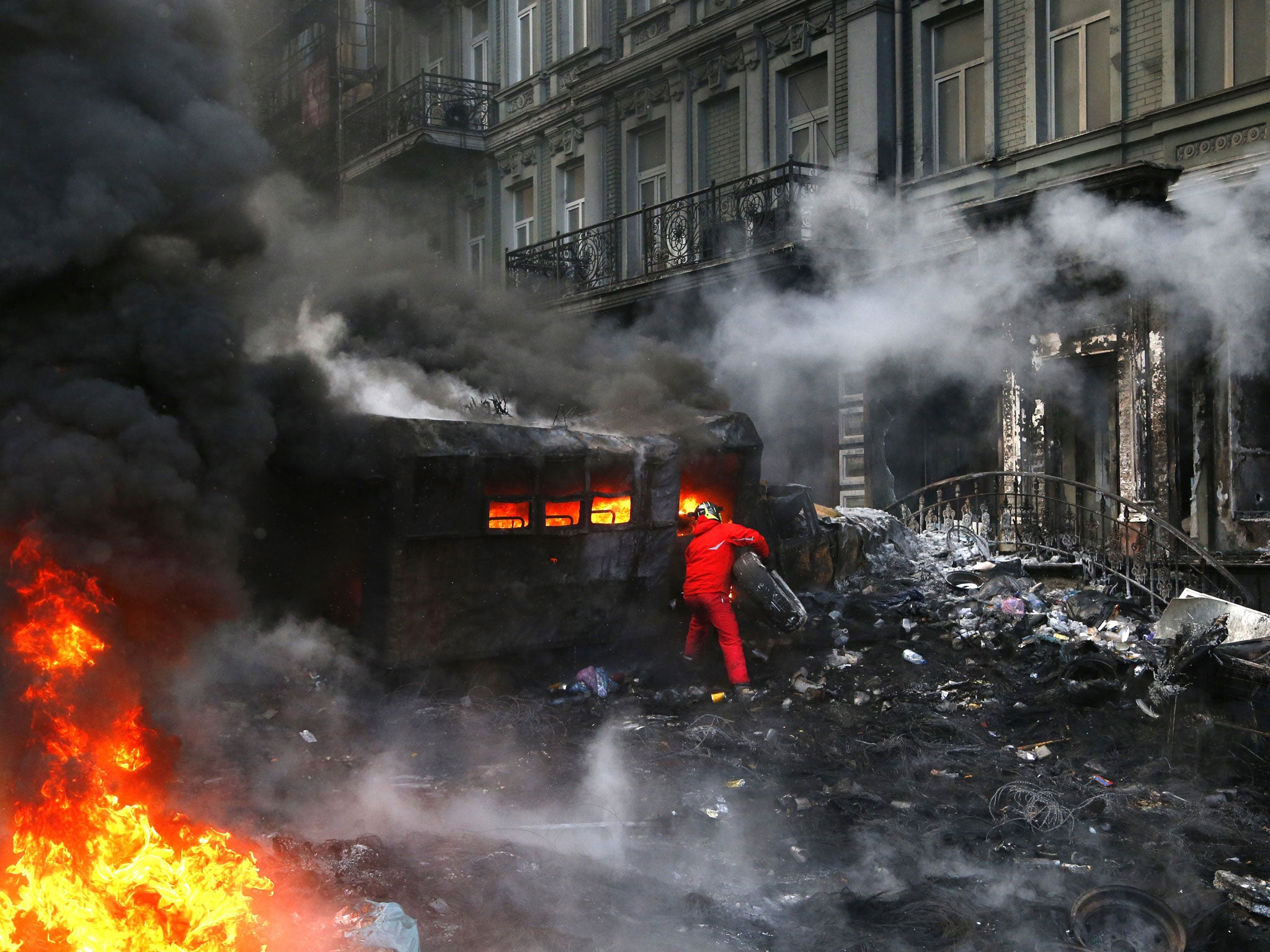 A protester added tyres to a fire during further clashes with police in central Kiev on Thursday, when thick black smoke engulfed parts of Ukraine's battered capital (AP)