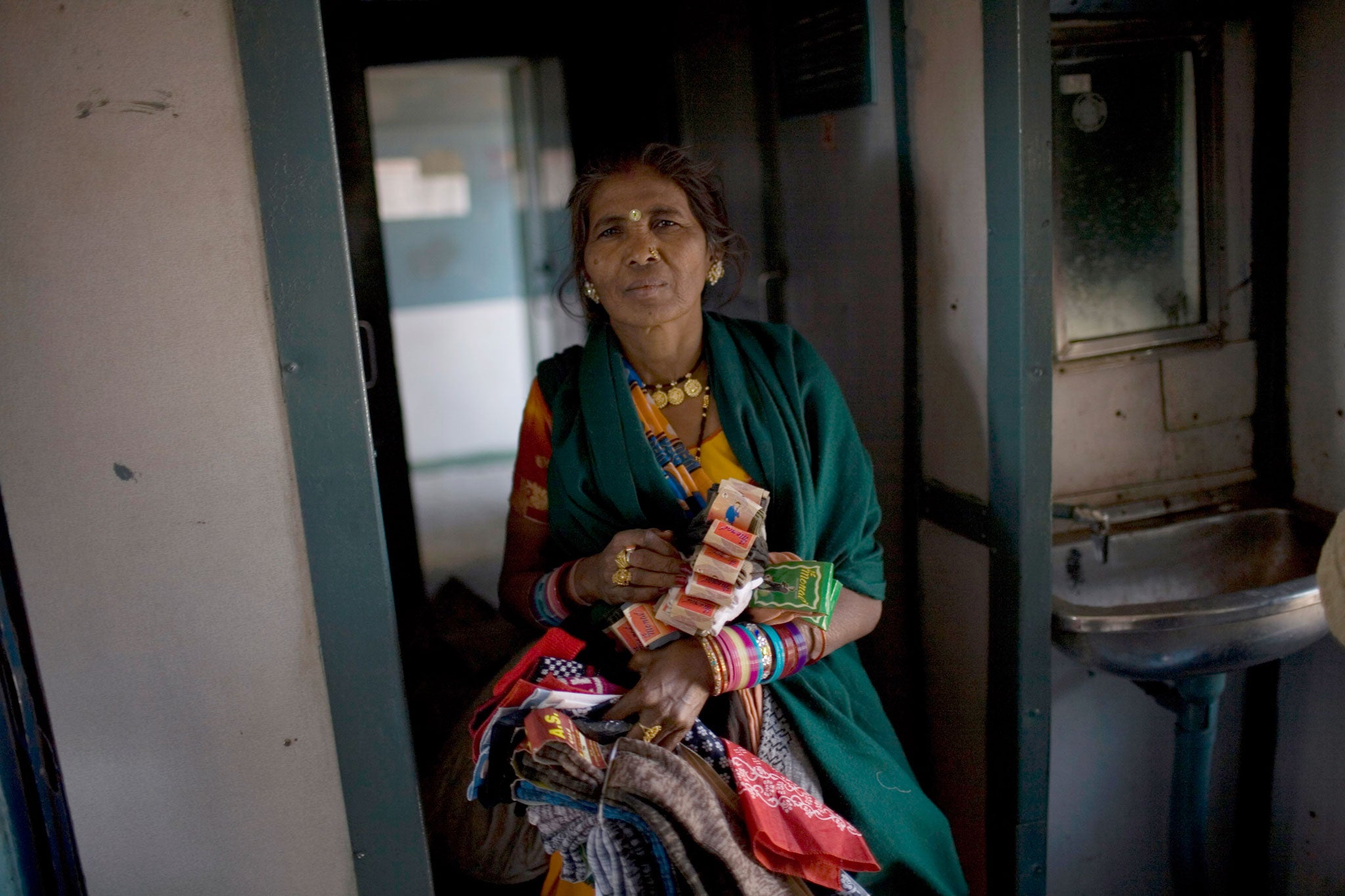 A woman sells socks, hats and handkerchiefs in a second class train carriage