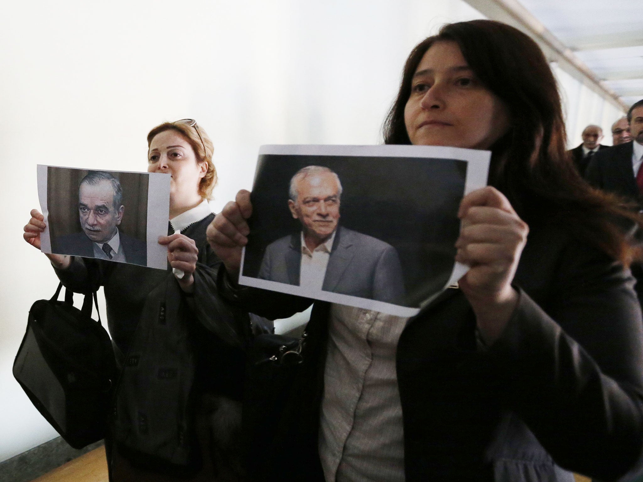 Syria opposition delegates, Suheir Attasi, left, and Rima Fleihan, hold pictures of two opposition members who are currently held in the Syrian government jail (Reuters)