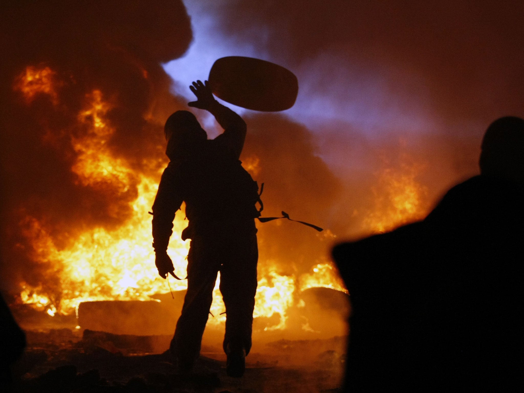 A protester throws a tire onto a fire in Kiev