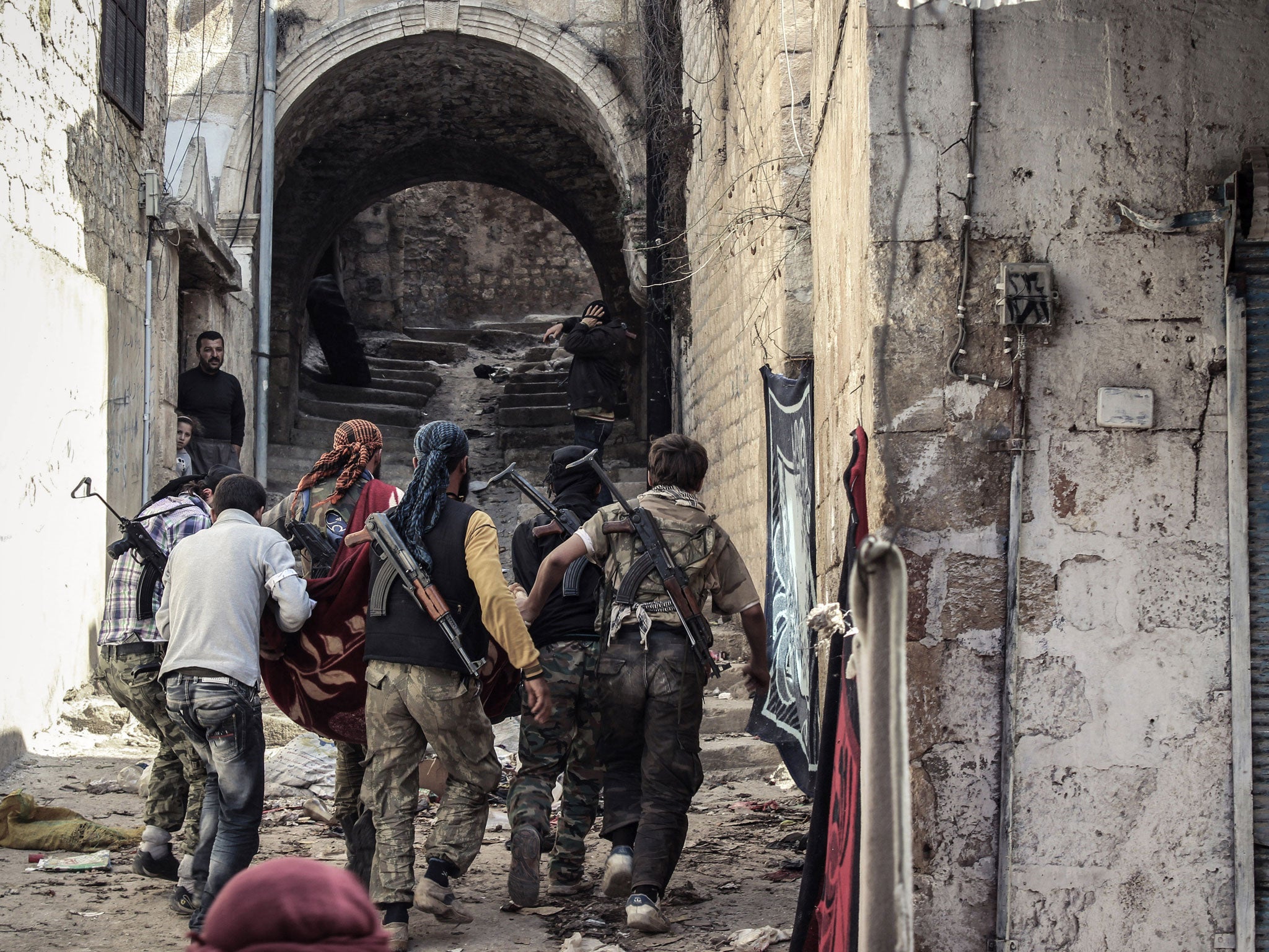 A group of Free Syrian Army fighters carry a wounded comrade to cover; over 16 people have been arrested since the beginning of the year amid rising fears of Britons being linked to fighting in Syria