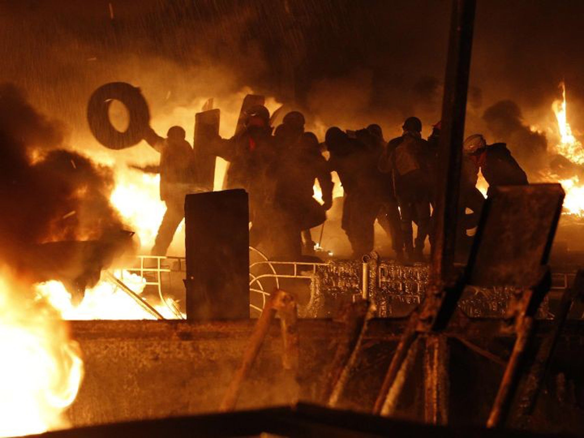 Anti-government protesters throw tyres at the site of clashes with riot police in Kiev