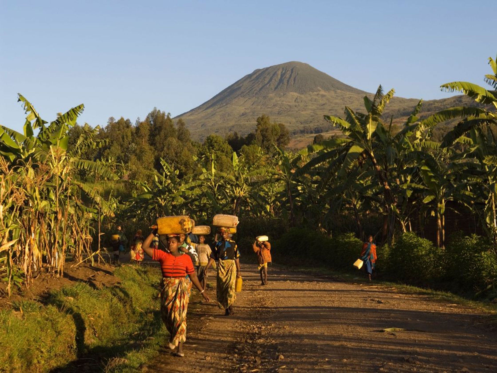 Women walk home with dormant volcano Muhabura in the background