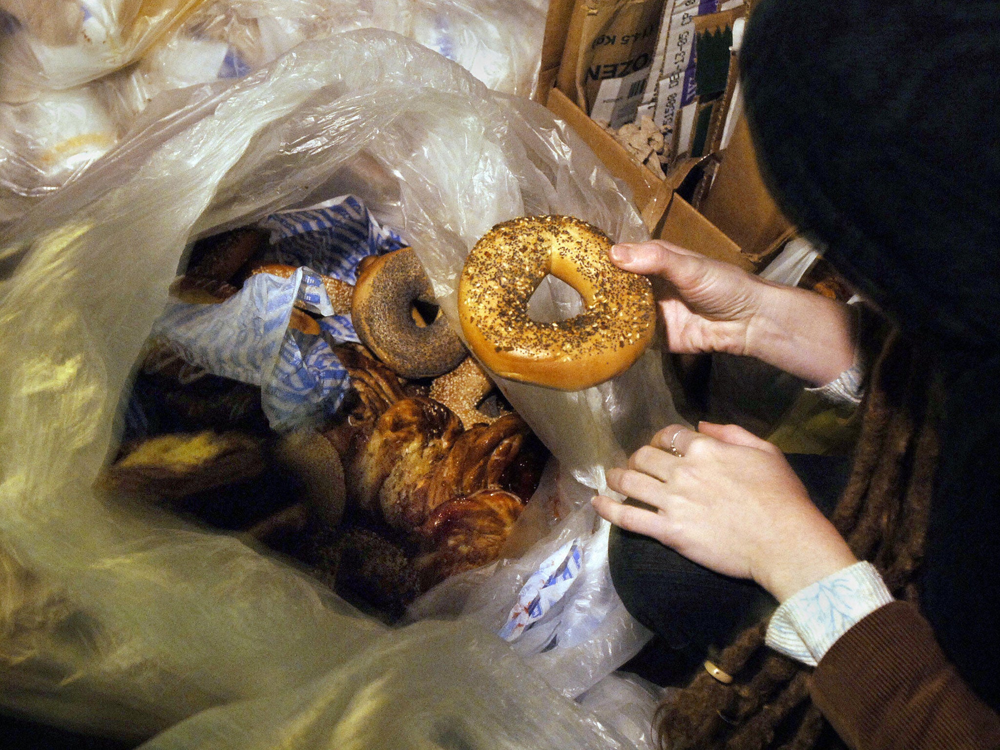 A woman part of a group of 'skipping freegans' finds a bagel in New York, allegedly the method used by the three men.