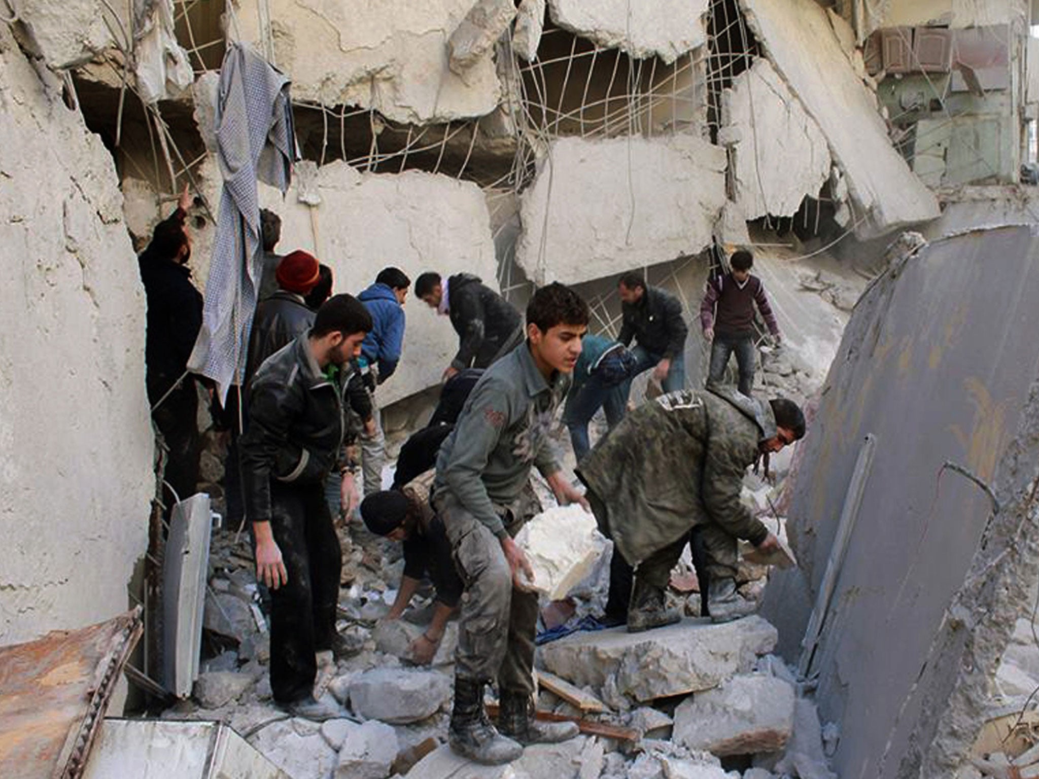 Syrians inspect the rubble of destroyed buildings following a Syrian government airstrike in Aleppo (AP)