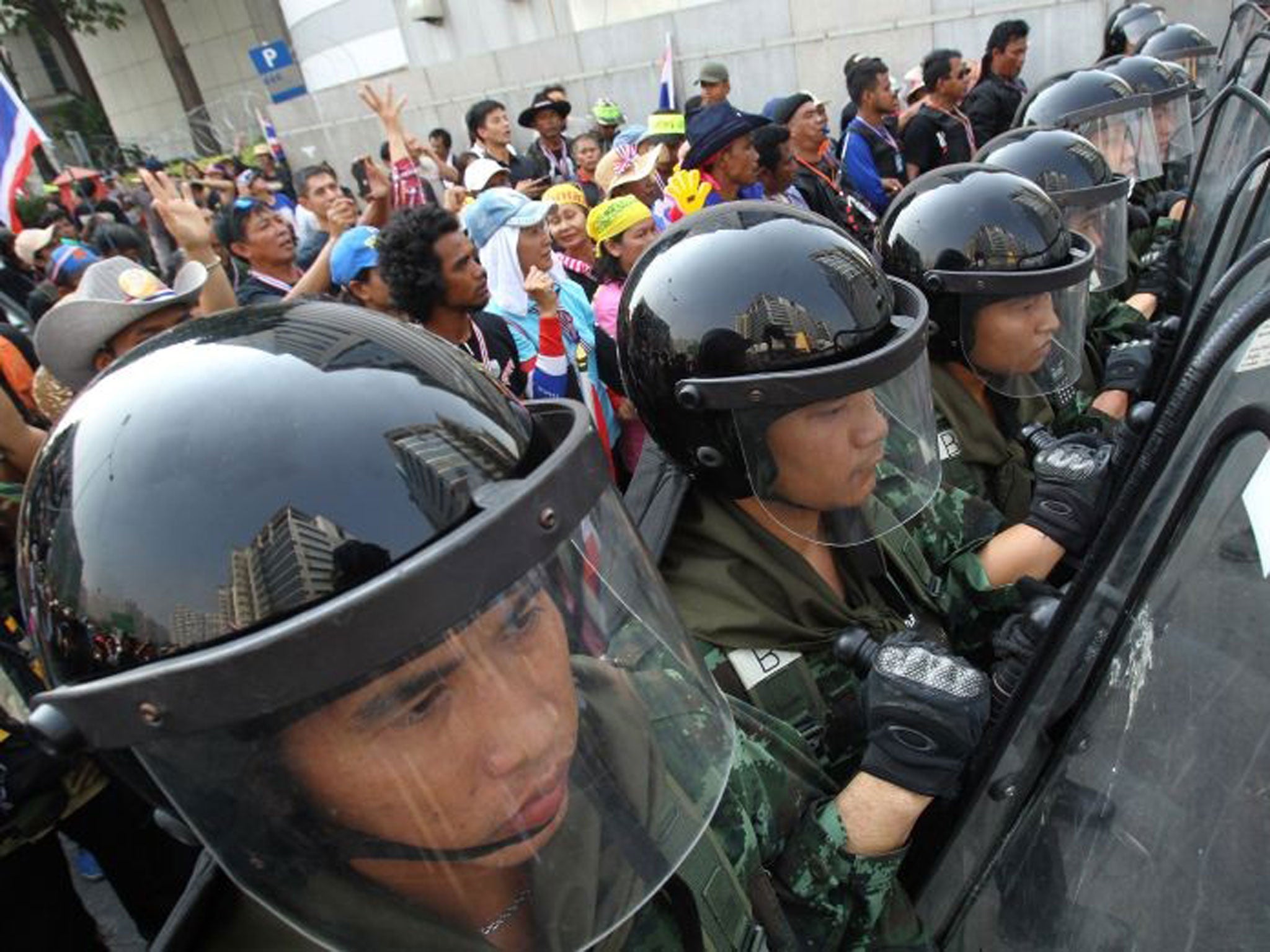 Thai soldiers stand guard to block anti-government protesters (left) during a rally outside the office of the permanent secretary for defense where Prime Minister Yingluck Shinawatra was reportedly working inside