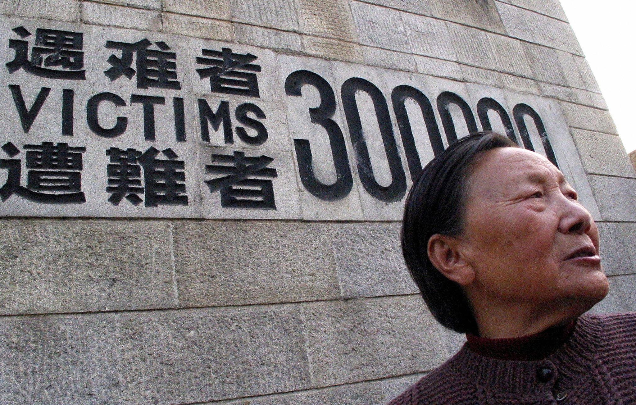 A man stands in front of the Monument for the Victims of the Nanjing Massacre.