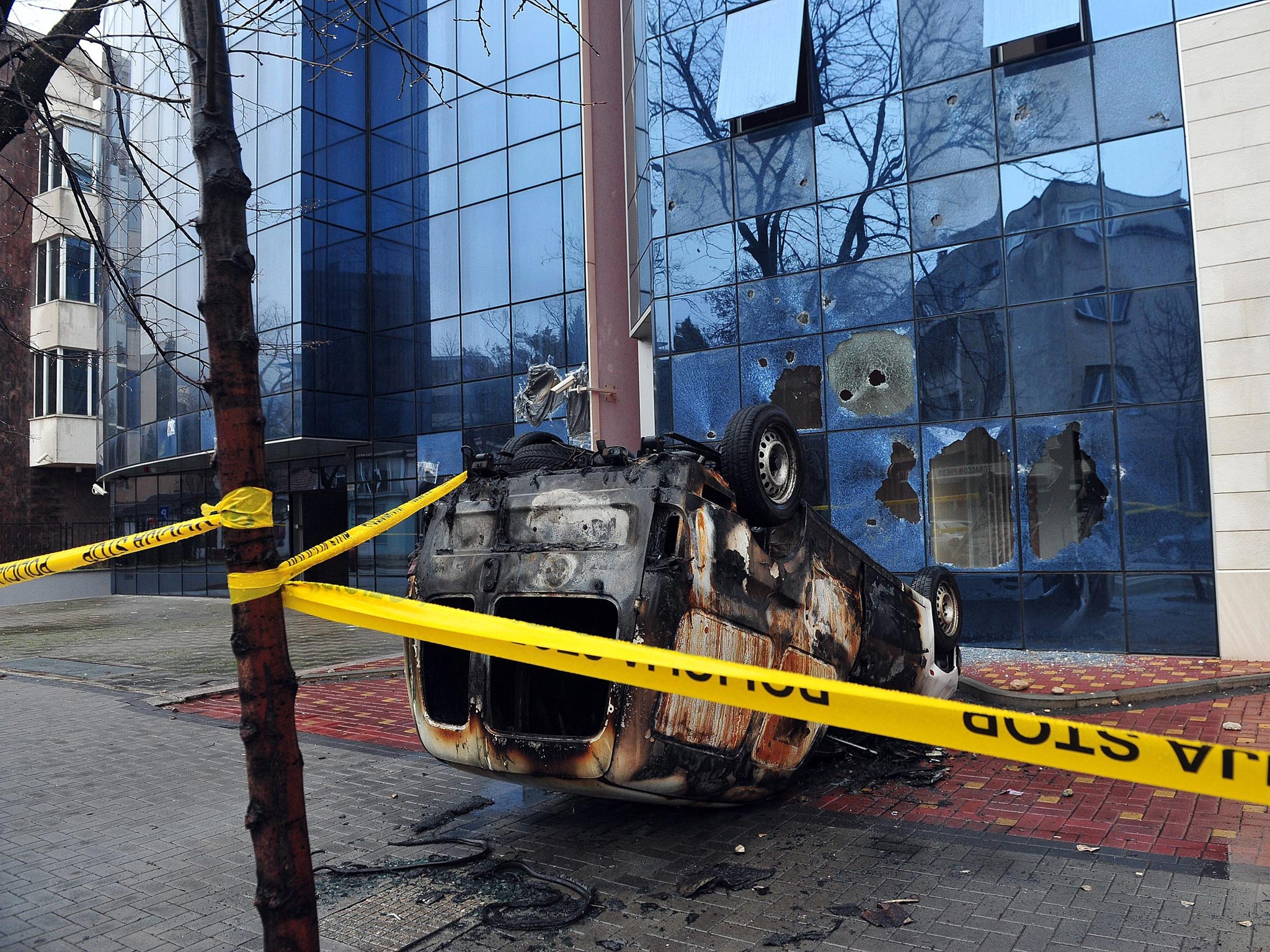 A burnt vehicle and windows broken by stones at the headquarters of the Croatian Democratic Union (HDZ) political party, in the Southern-Bosnian town of Mostar