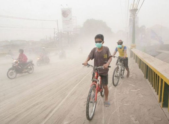 Indonesian residents ride their bikes on a street covered with ash from the Mount Kelud volcano in Yogyakarta (EPA)