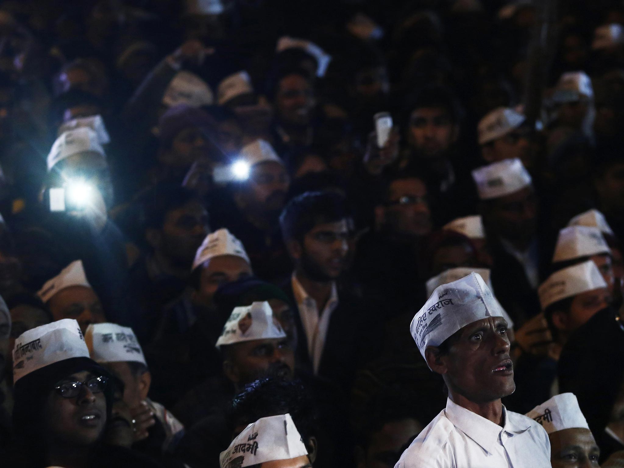 Supporters of Delhi's Chief Minister Arvind Kejriwal, chief of the Aam Aadmi (Common Man) Party (AAP), listen to his speech