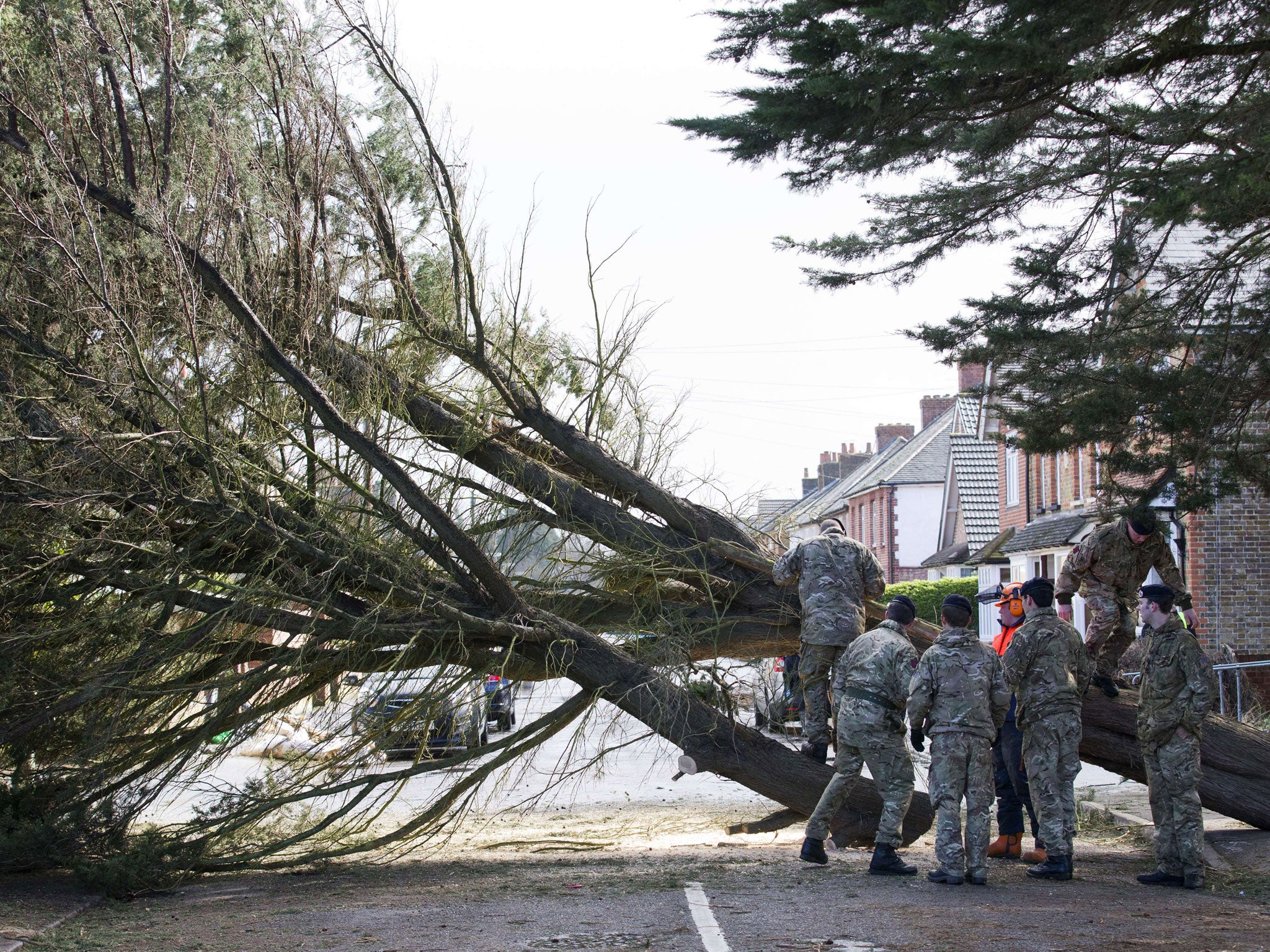 British soliders help a tree surgeon remove a fallen tree in Egham, west of London