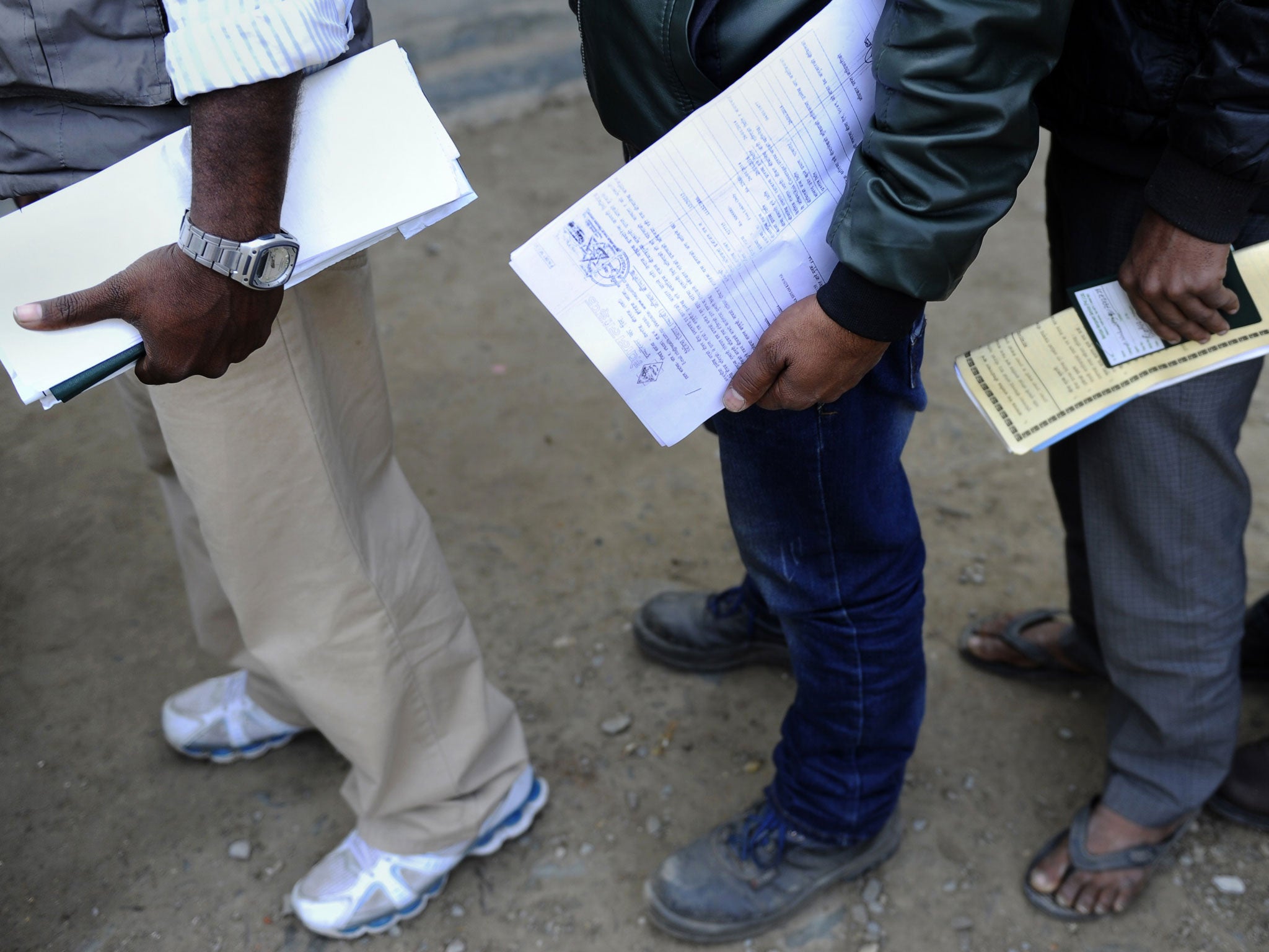 Nepalese migrant workers queue to receive official documents in order to leave Nepal for Qatar.