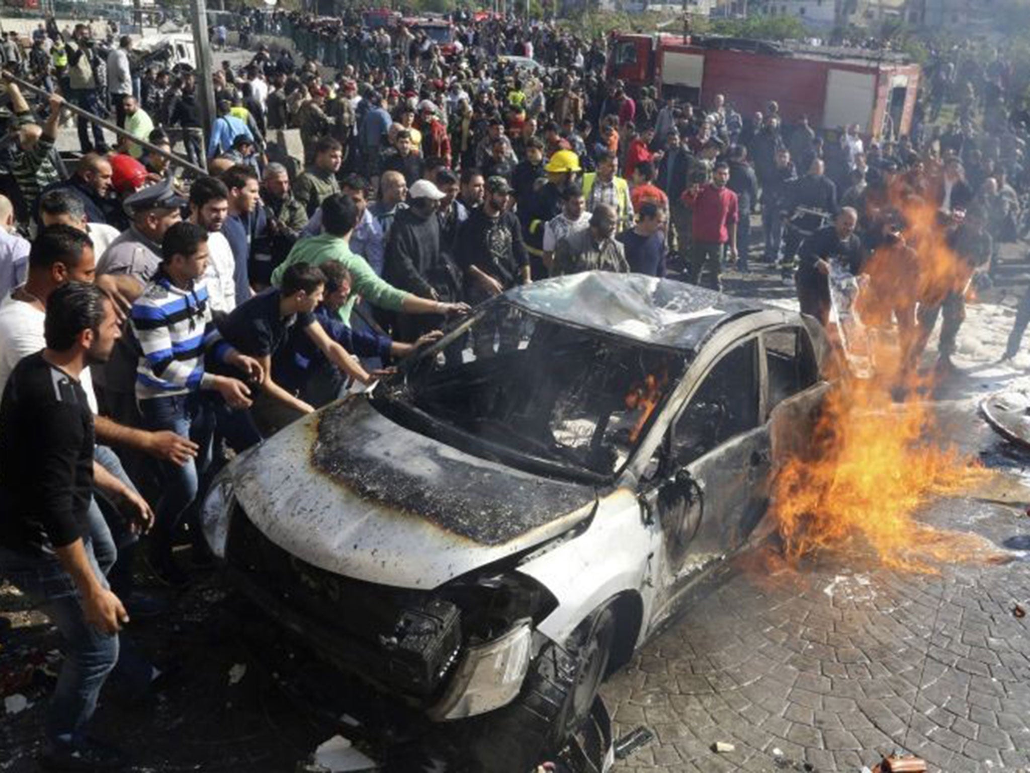 Civil defence members and civilians attempt to extinguish the fire at the site of the blast