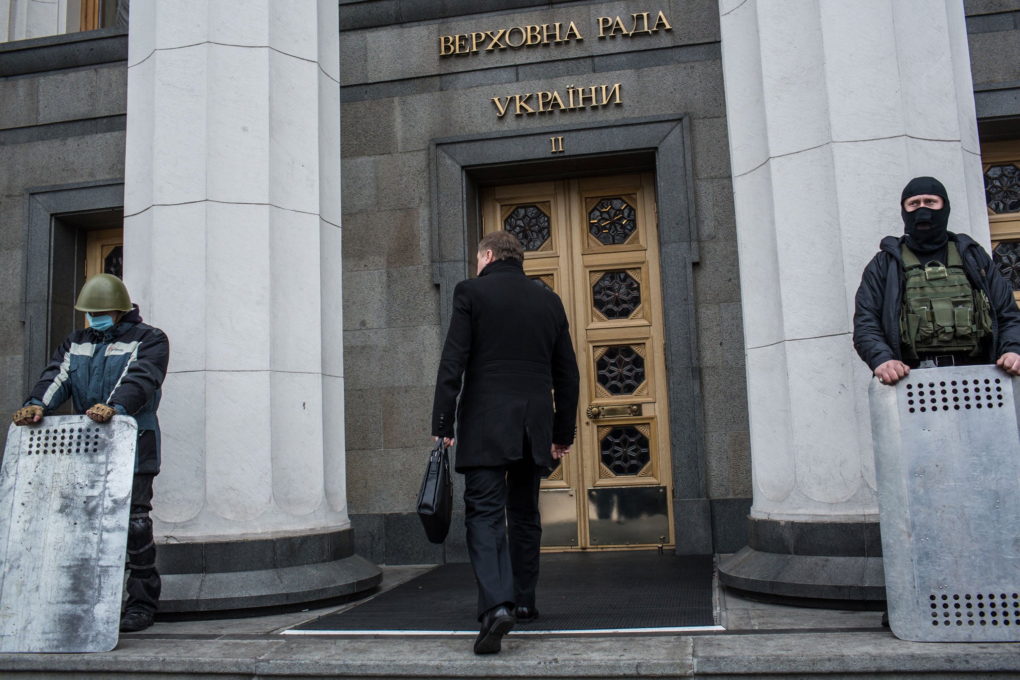 A man enters the Ukrainian parliament, guarded by anti-government protesters, ahead of a session on 22 February 2014 in Kiev. Ukrainian MPs voted yesterday to oust Viktor Yanukovych and bring presidential elections forward to the 25 May