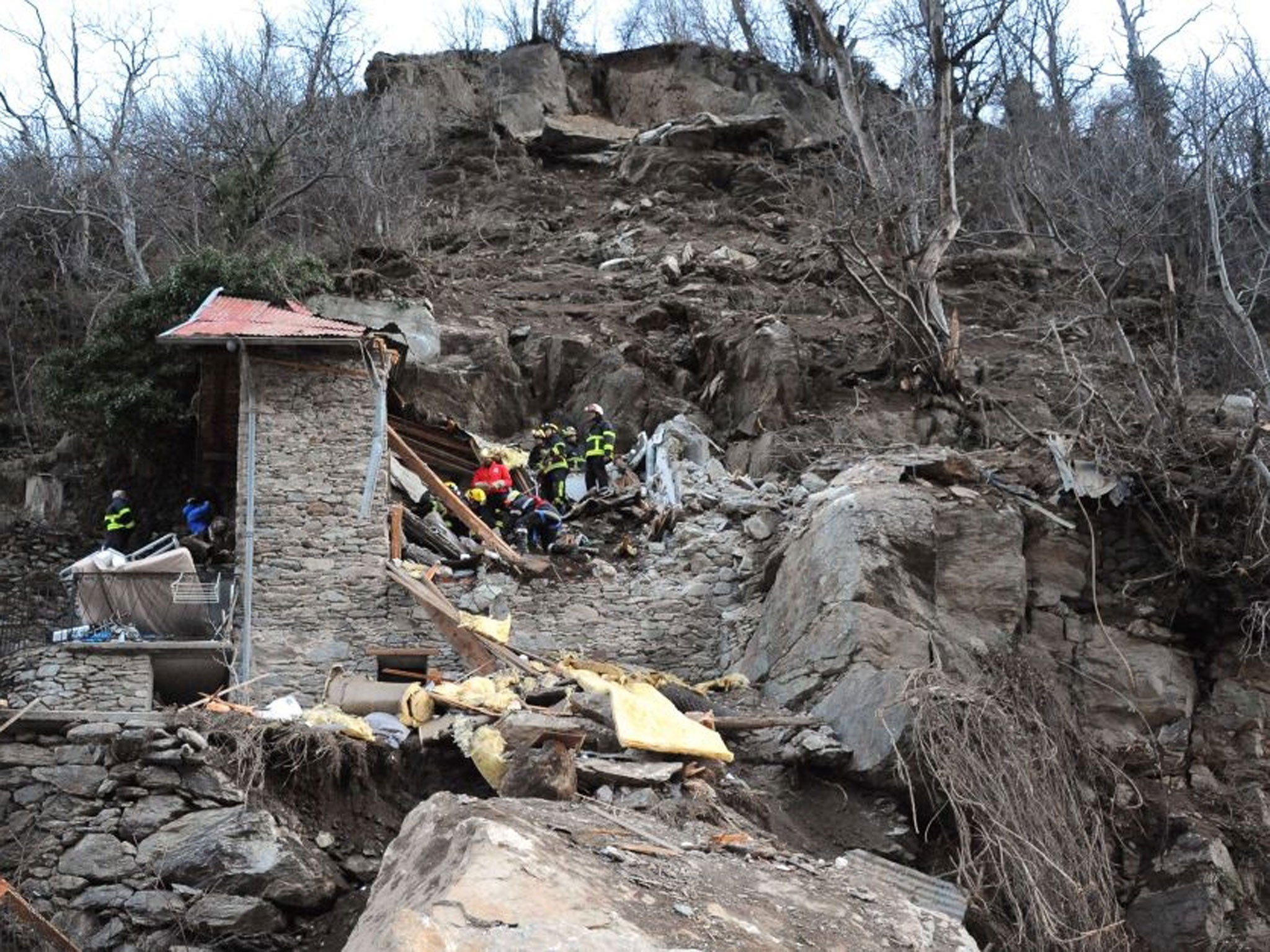 Firefighters work in front of a mountain cottage after a rockslide killed two children aged seven and ten, 23 February 23, 2014 in Isola Village.