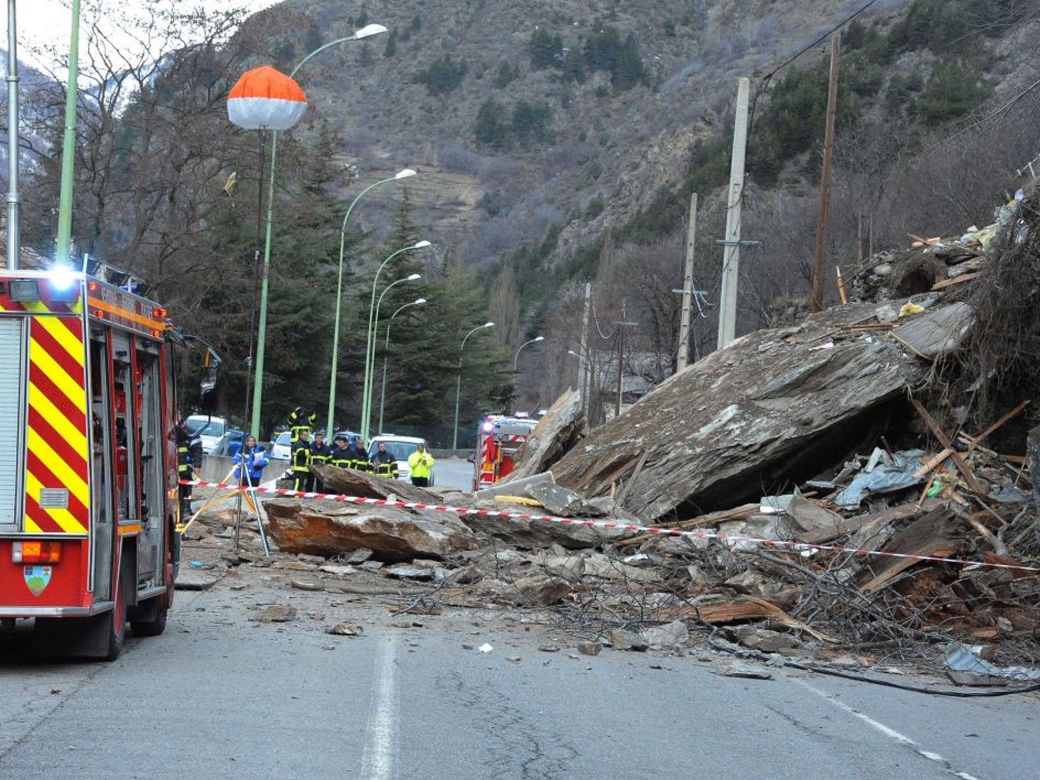 Firefighters work in front of a mountain cottage after a rockslide killed two children aged seven and ten