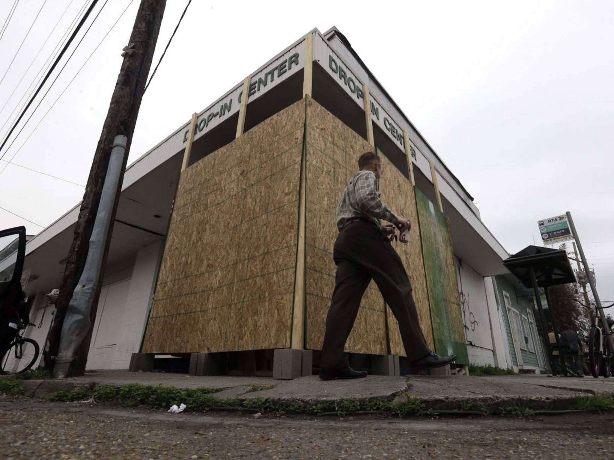 People walk past a plywood barrier protecting a mural by the artist Banksy, in New Orleans.