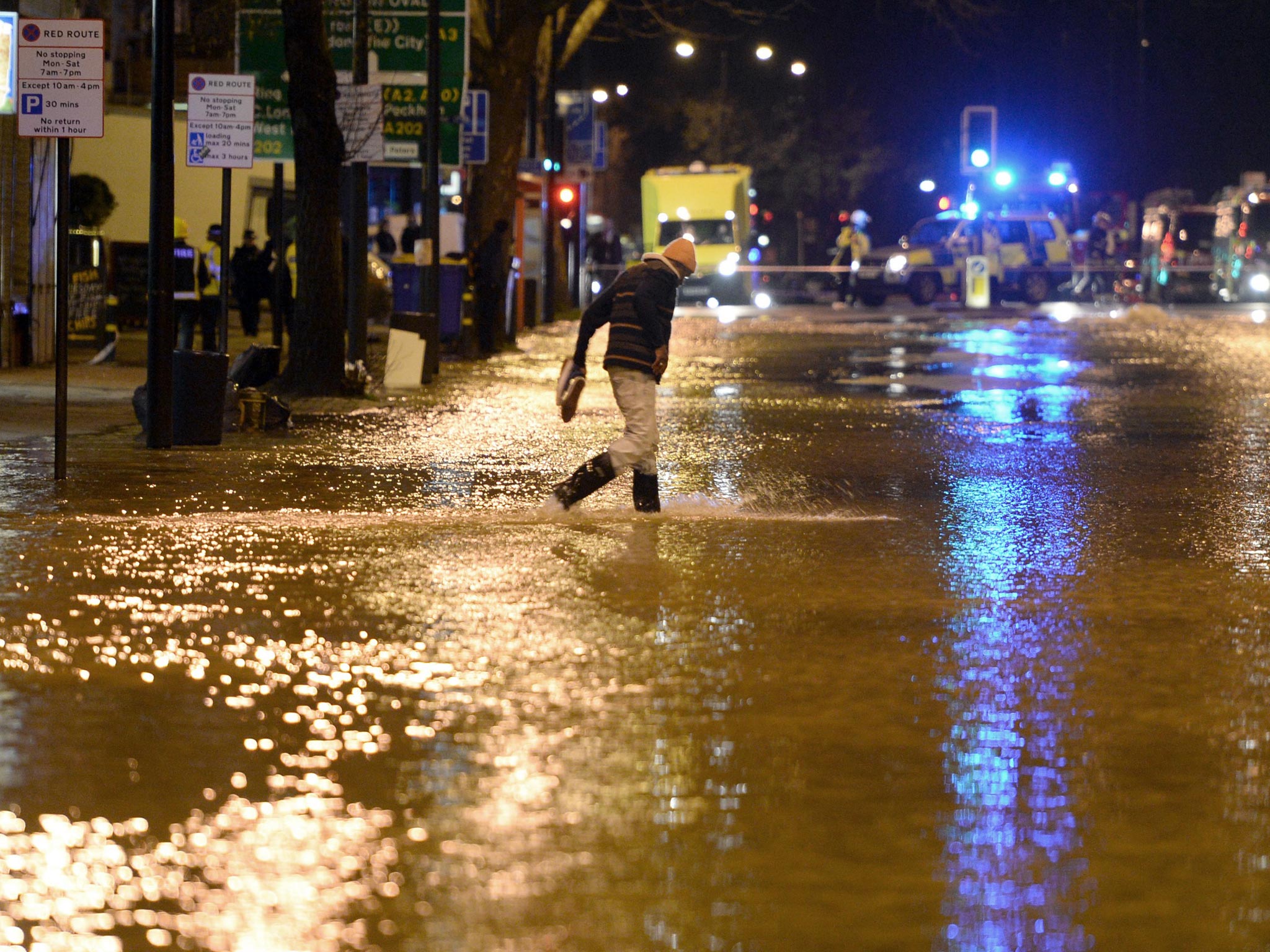 A man walks through flood water from a burst main in Clapham Road in Kennington, south London.