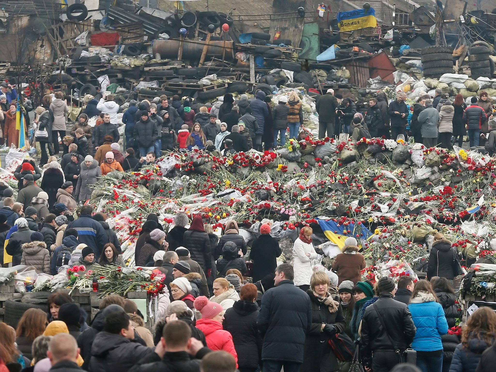 Ukrainians encircle an area filled with floral ltributes and candles as they remember those killed during the recent violent protests, in Kiev, Ukraine