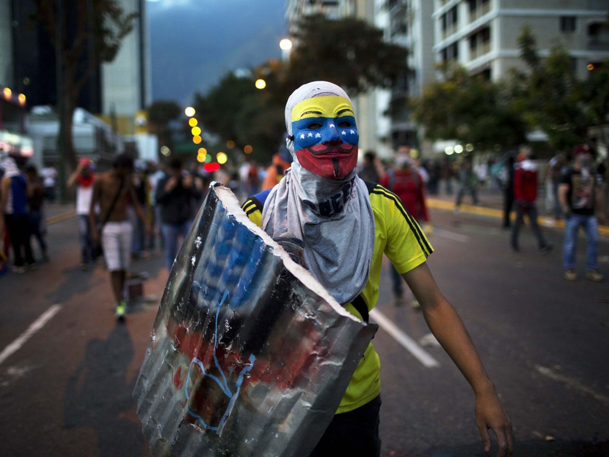 An anti-government demonstrator walks towards riot policemen during a protest in Caracas last night