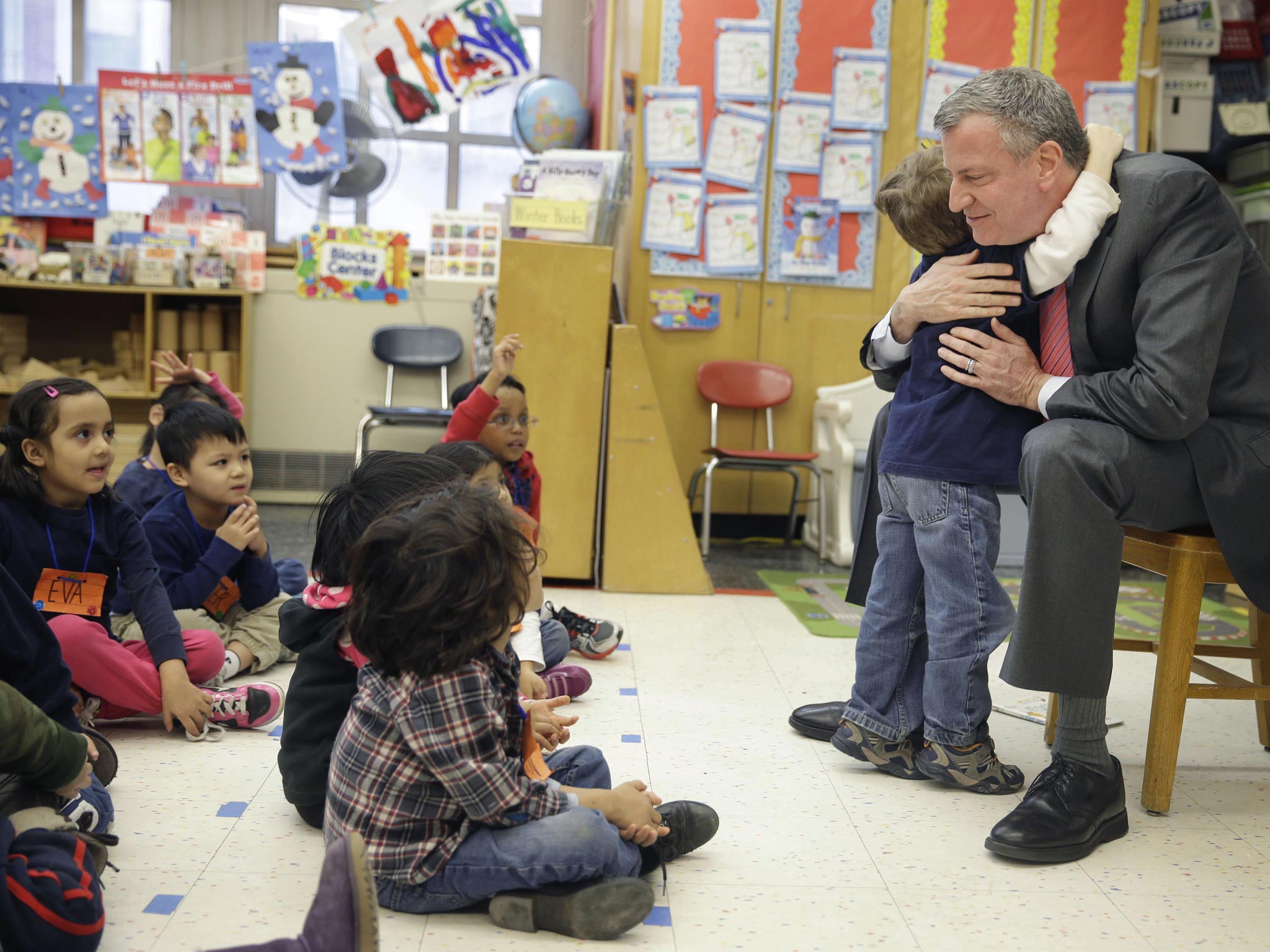 New York City Mayor Bill de Blasio hugs a child after reading a book to a prekindergarten class