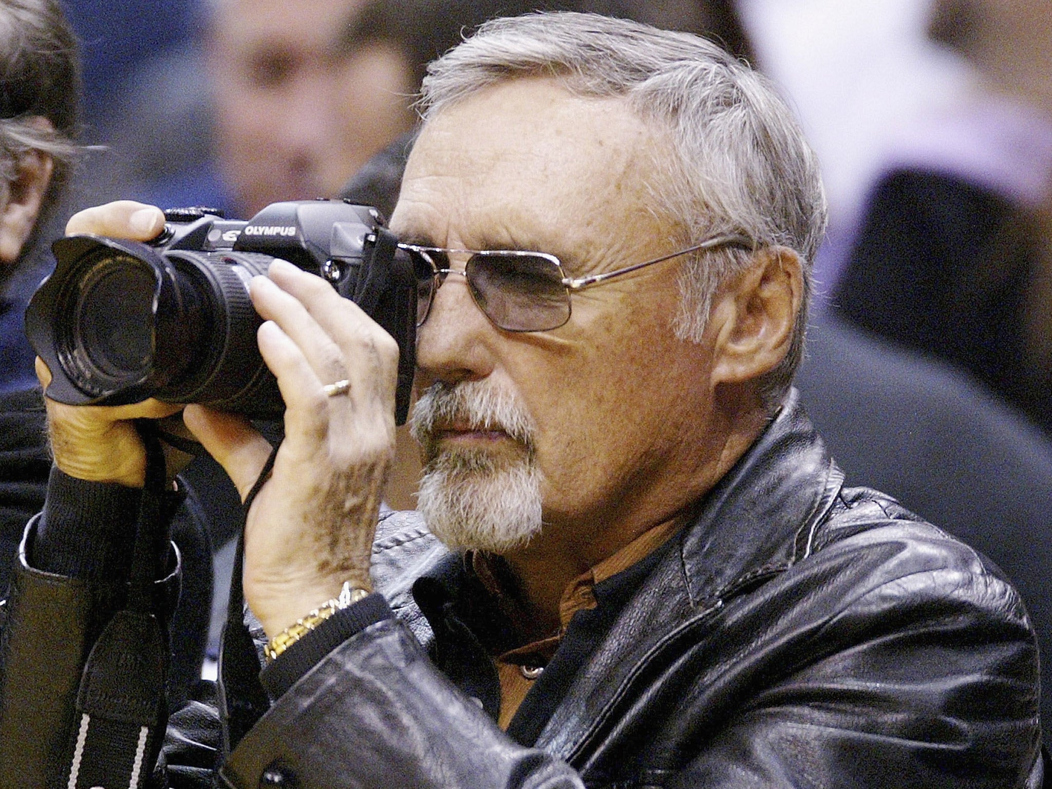 Actor Dennis Hopper focuses his camera at a basketball game (Getty)