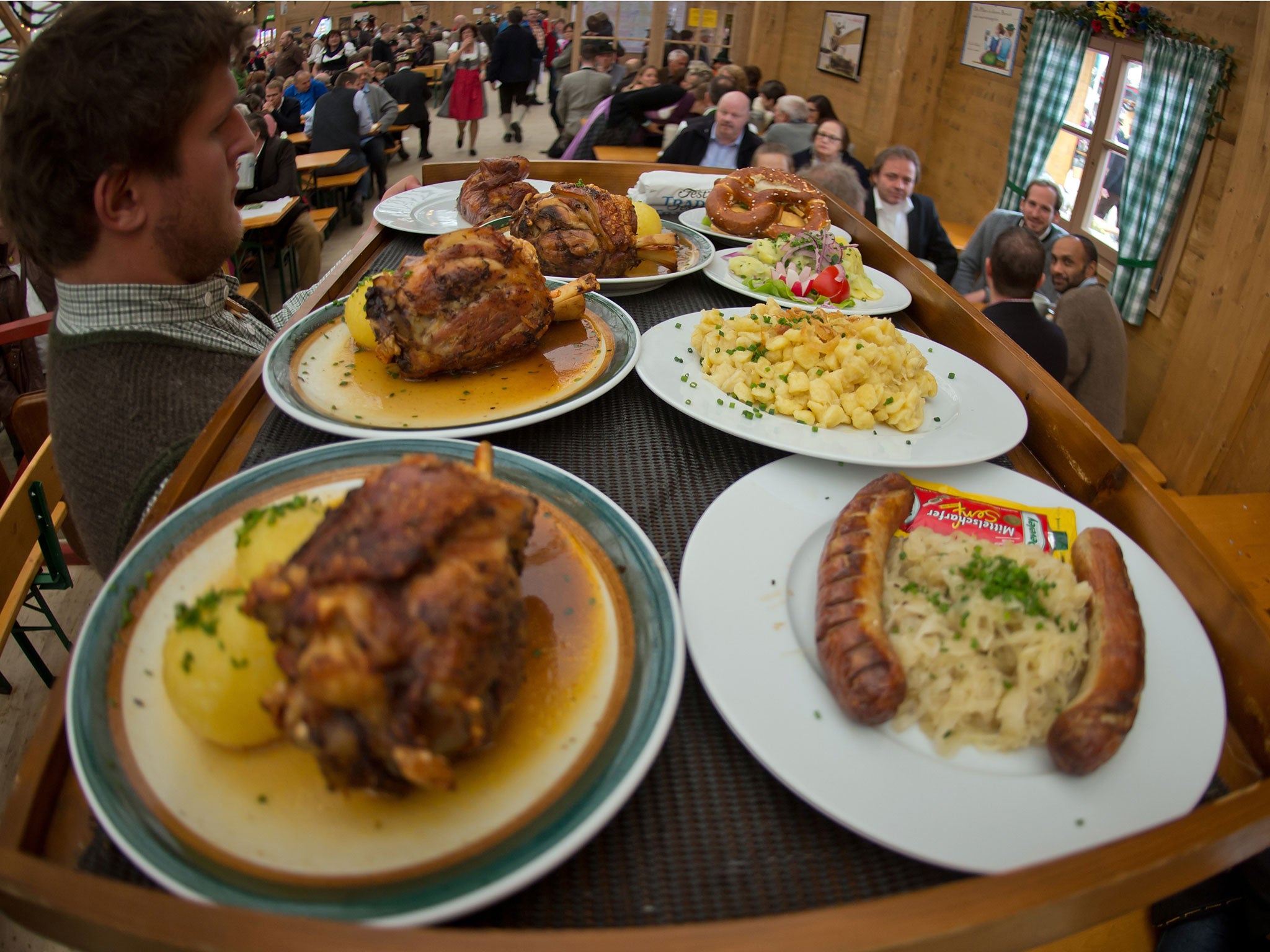 A waiter carries a large tray of meals.