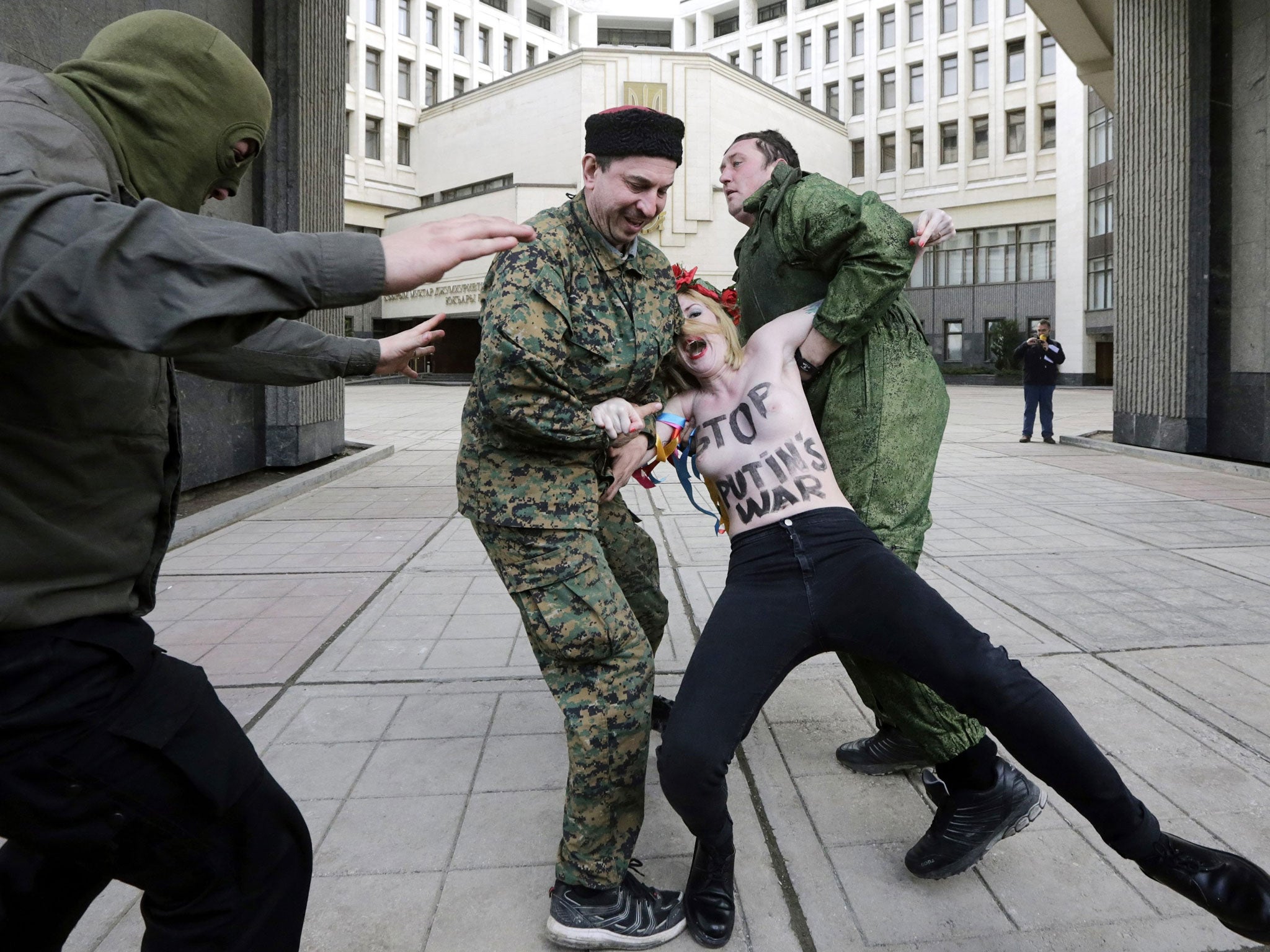 Pro-Russian activists believed to be Cossaks detain a member of the feminist group FEMEN protesting against Putin's policy concerning Ukraine during a pro-Russian rally near the Crimea's parliment in Simferopol, Ukraine, 06 March 2014.