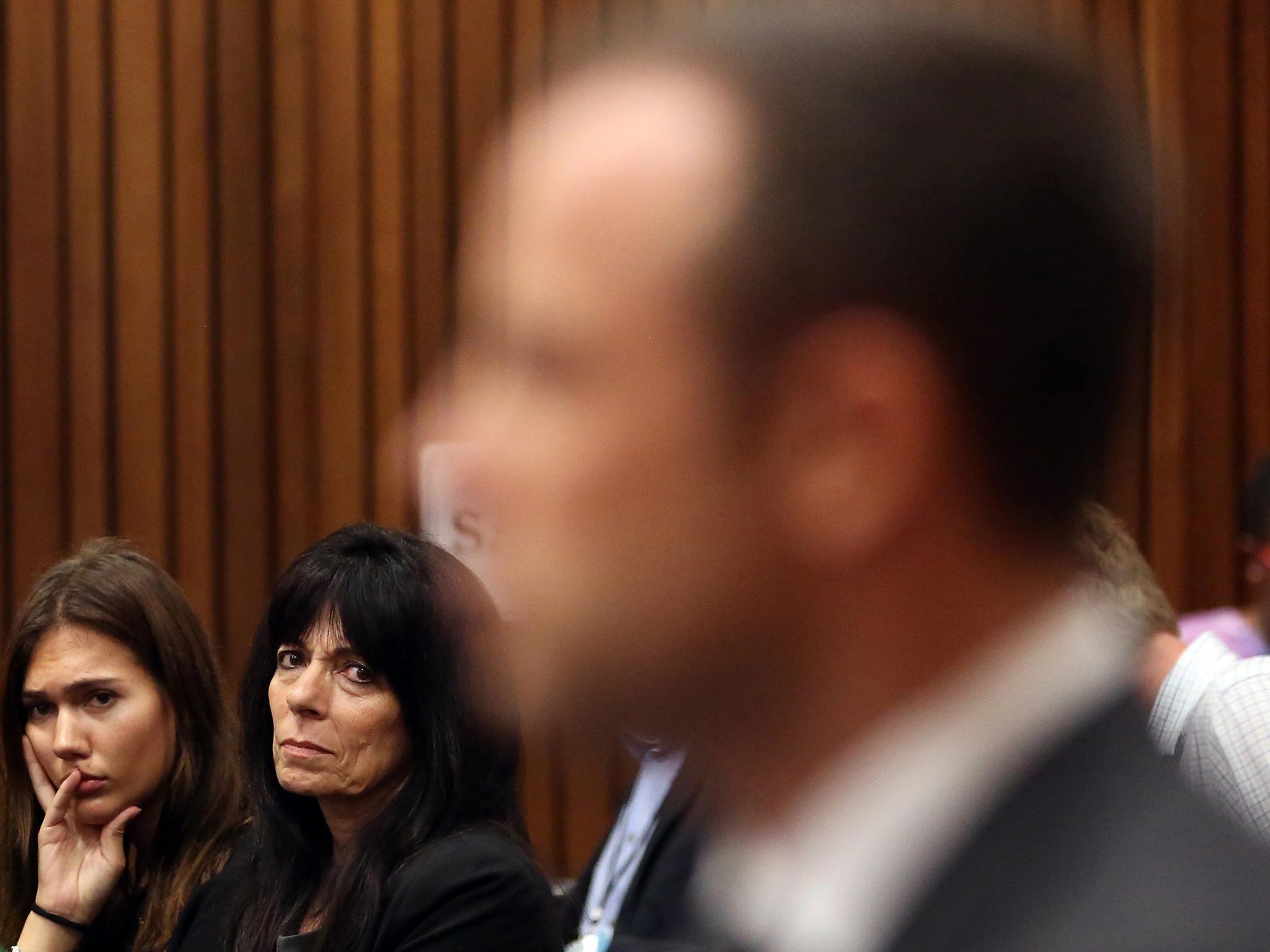 Family friends of Reeva Steenkamp glance at Oscar Pistorius, foreground, during his trial at the high court in Pretoria