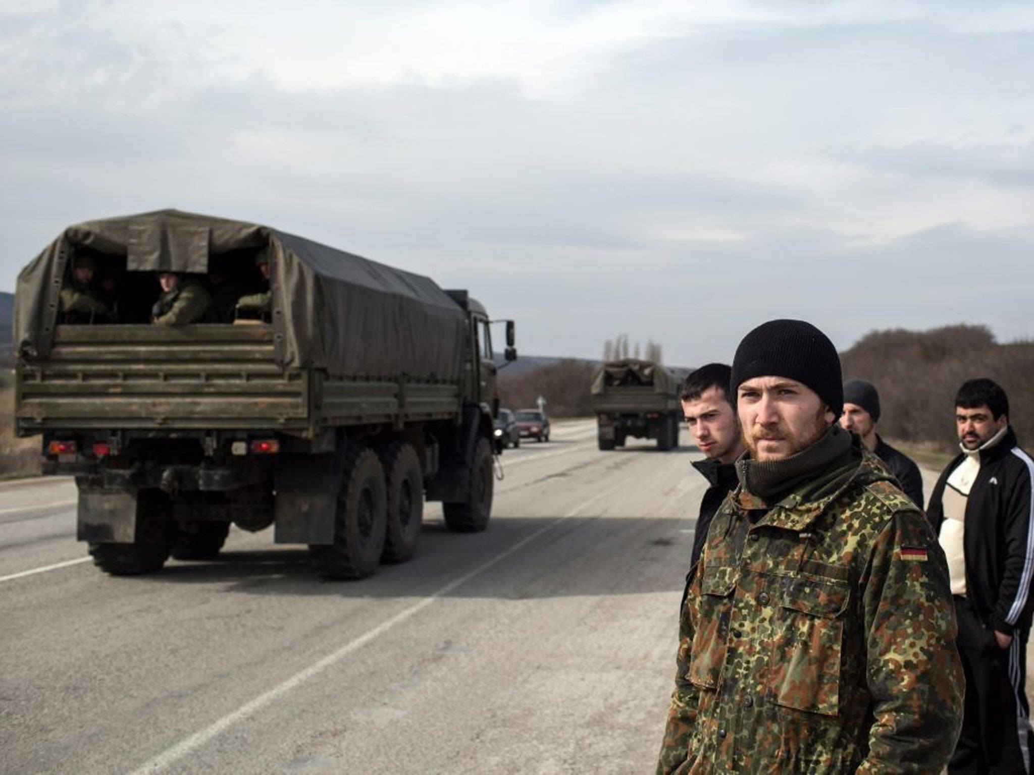 Crimean ethnic tatars stand on the roadside as Russian troops move towards to Simferopol in the settlement of Kok-Asan, some 70 kilometres from Simferopol in Crimea.