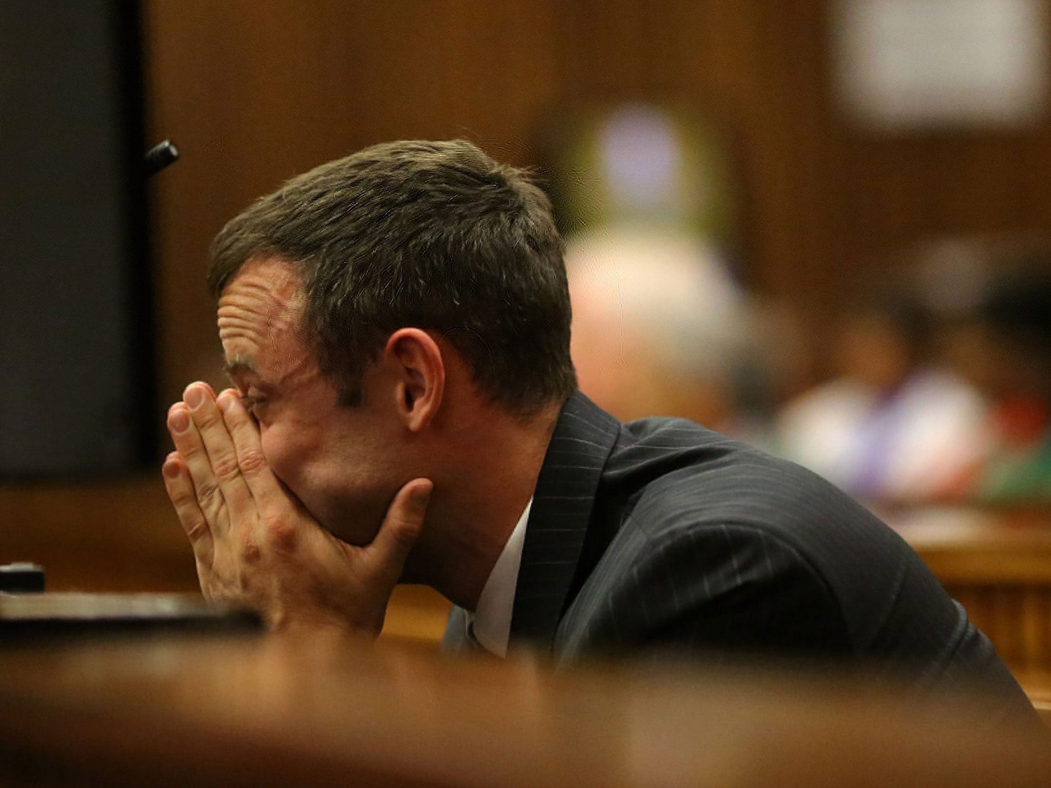 Oscar Pistorius holds his hands to his face as he sits in the dock during day 6 of his murder trial at the High Court in Pretoria